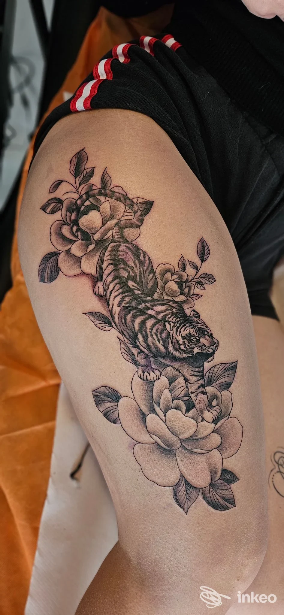 Tattoo realistico in bianco e nero di una tigre in mezzo a fiori sulla coscia, fotografato per Red rose tattoo studio, Modugno.