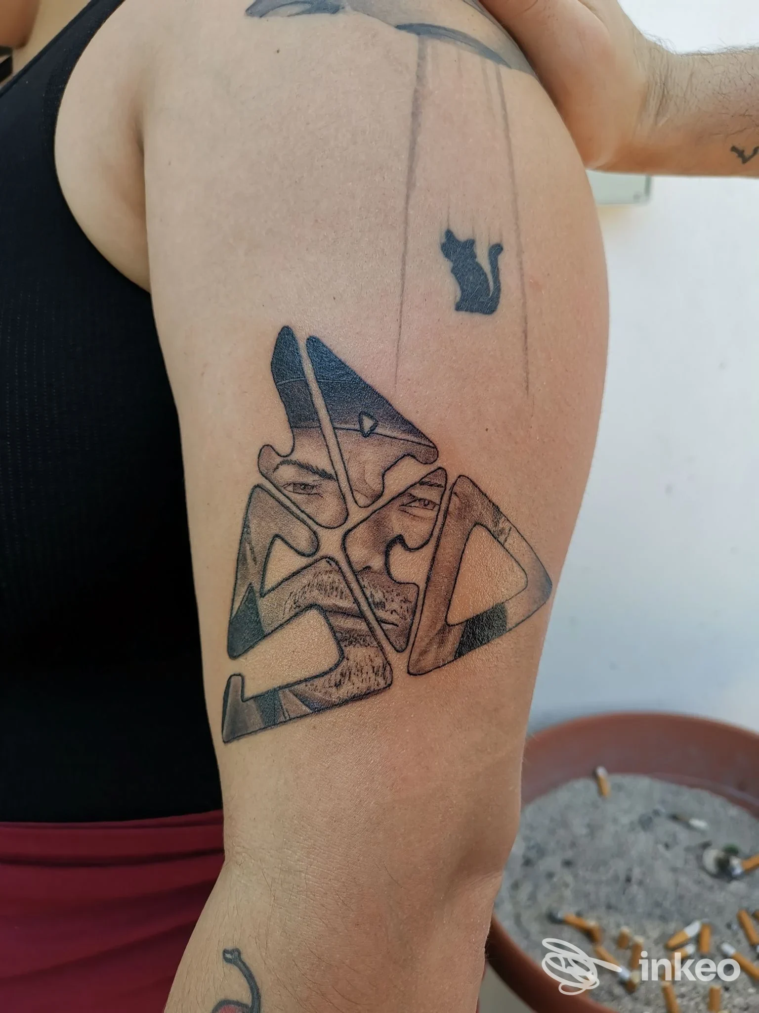 Tatuaggi neri geometrici su braccio superiore, con piccolo gatto stilizzato – Erion Tattoo di Meca Erion, Ripi.