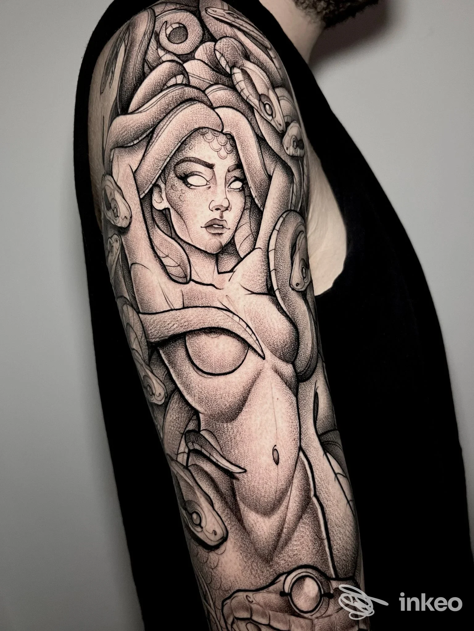 Tattoo a braccio su pelle nera, raffigurante una donna stilizzata circondata da elementi ornamentali, eseguito in tonalità nere e grigie; foto priva di sovrimpressioni o elementi di testo.