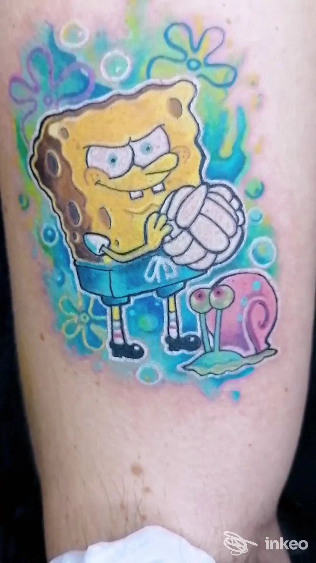 Tatuaggio colorato di SpongeBob e la lumaca Gary sul polpaccio, lavoro dello studio Blue Spring a Genova.