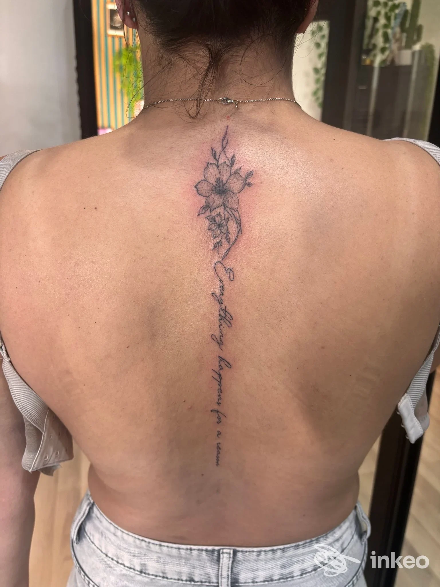 Tatuaggio verticale con fiori e scritta lungo la colonna sulla schiena, foto fornita da Br.ink tattoo a Sora.