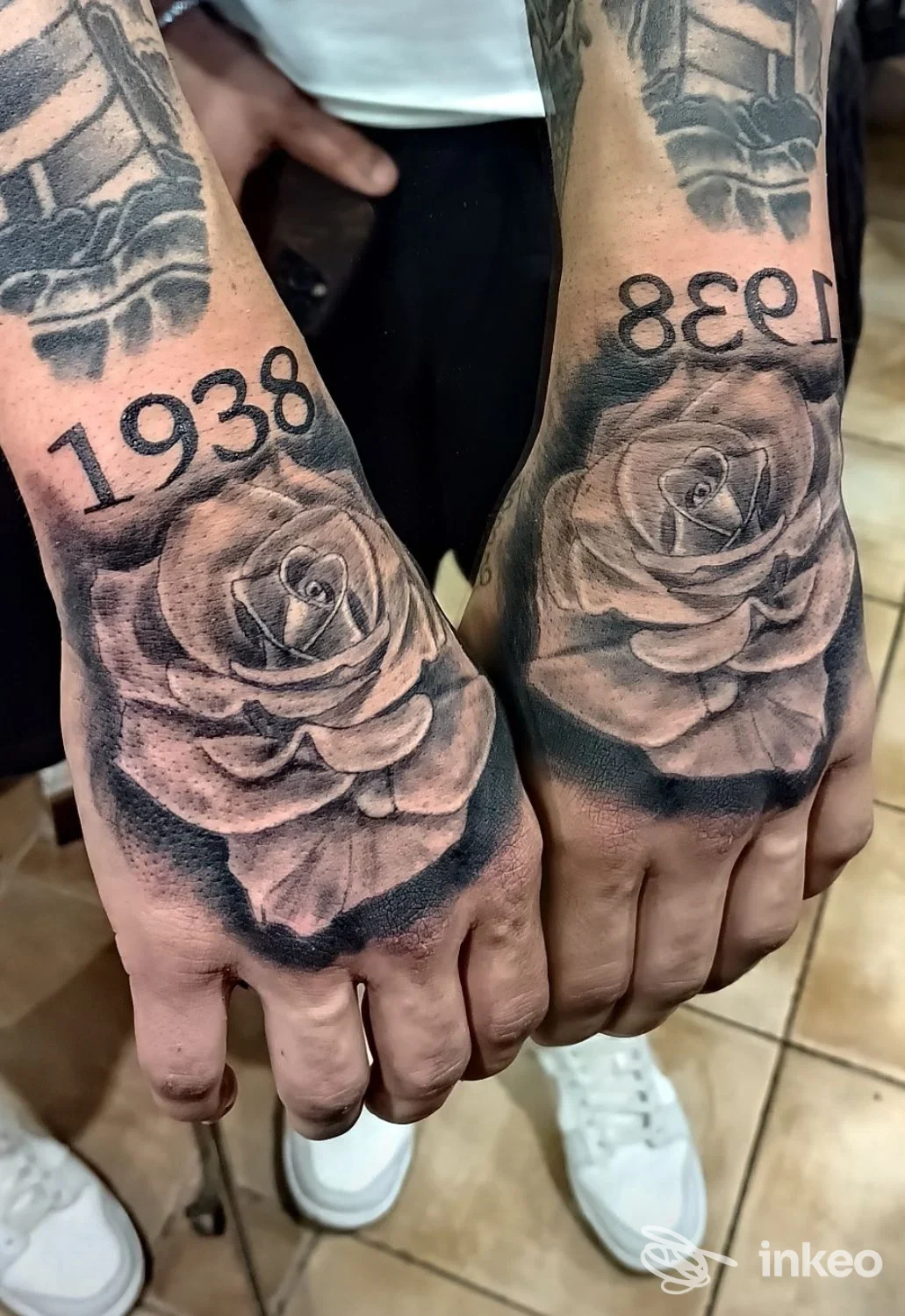 Due mani tatuate con rose realistiche in nero-grigio e numeri '1938', foto per tattoo e piercing roma a Roma.