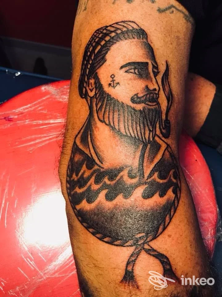 Tatuaggio su avambraccio raffigurante uomo barbato con pipa e onde, foto fornita da Titti Tattoo a Viterbo.