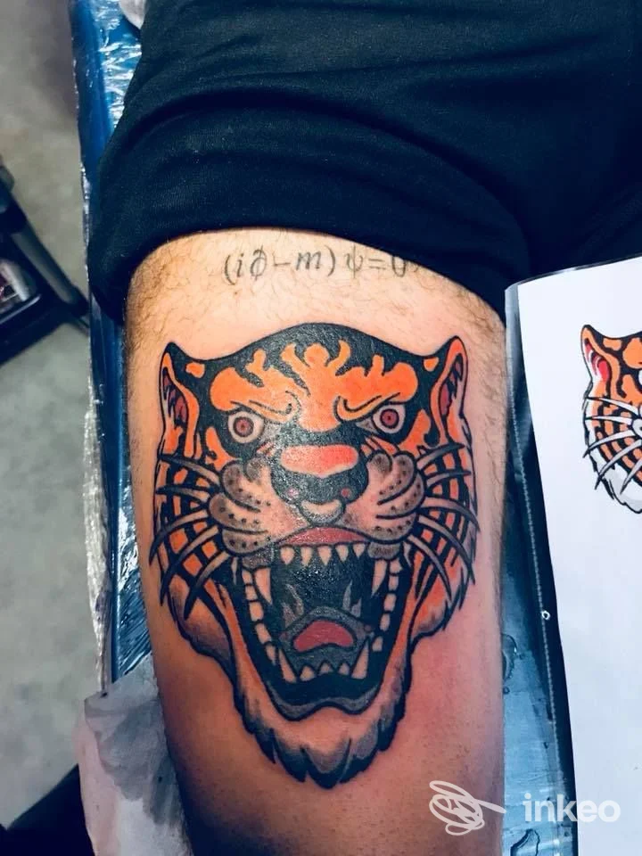 Grande tatuaggio tradizionale a testa di tigre sul quadricipite, linee nette e colori pieni, eseguito da Titti Tattoo a Viterbo.