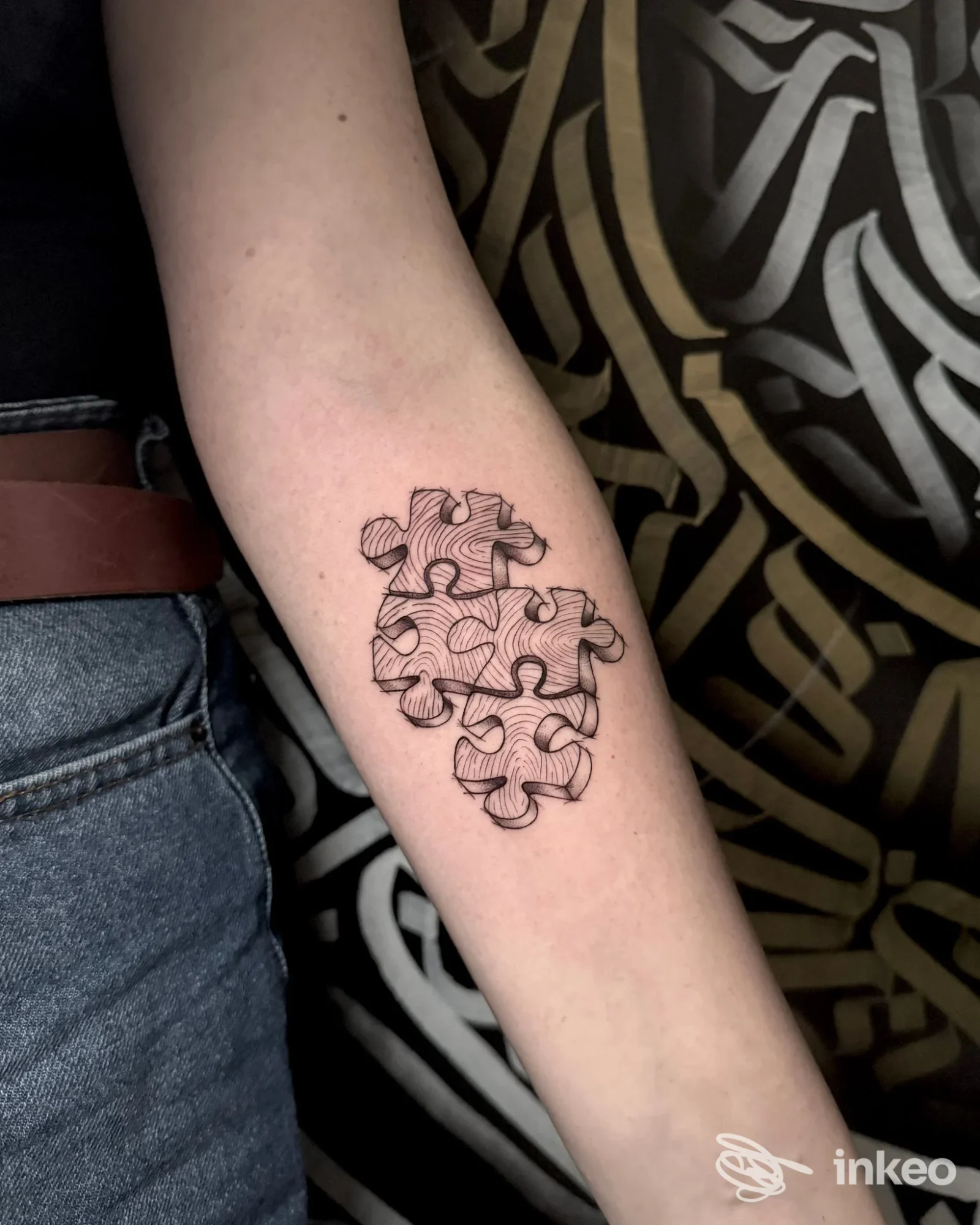 Tatuaggio a pezzi di puzzle in nero sull'avambraccio, foto fornita da Black Queen Tattoo, Oderzo.