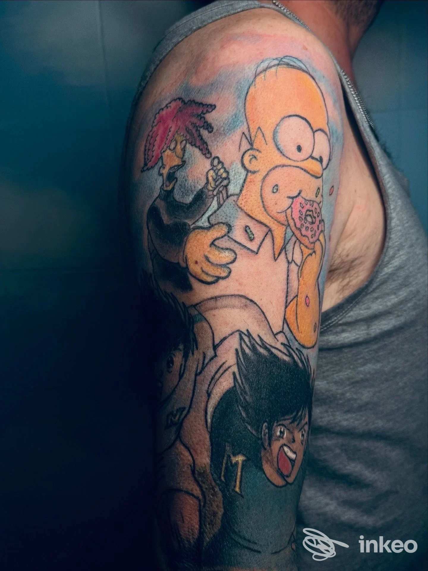 Tatuaggio a manica parziale sul braccio con Homer Simpson e altri personaggi, realizzato da Seven Eleven Ink a Castro dei Volsci.
