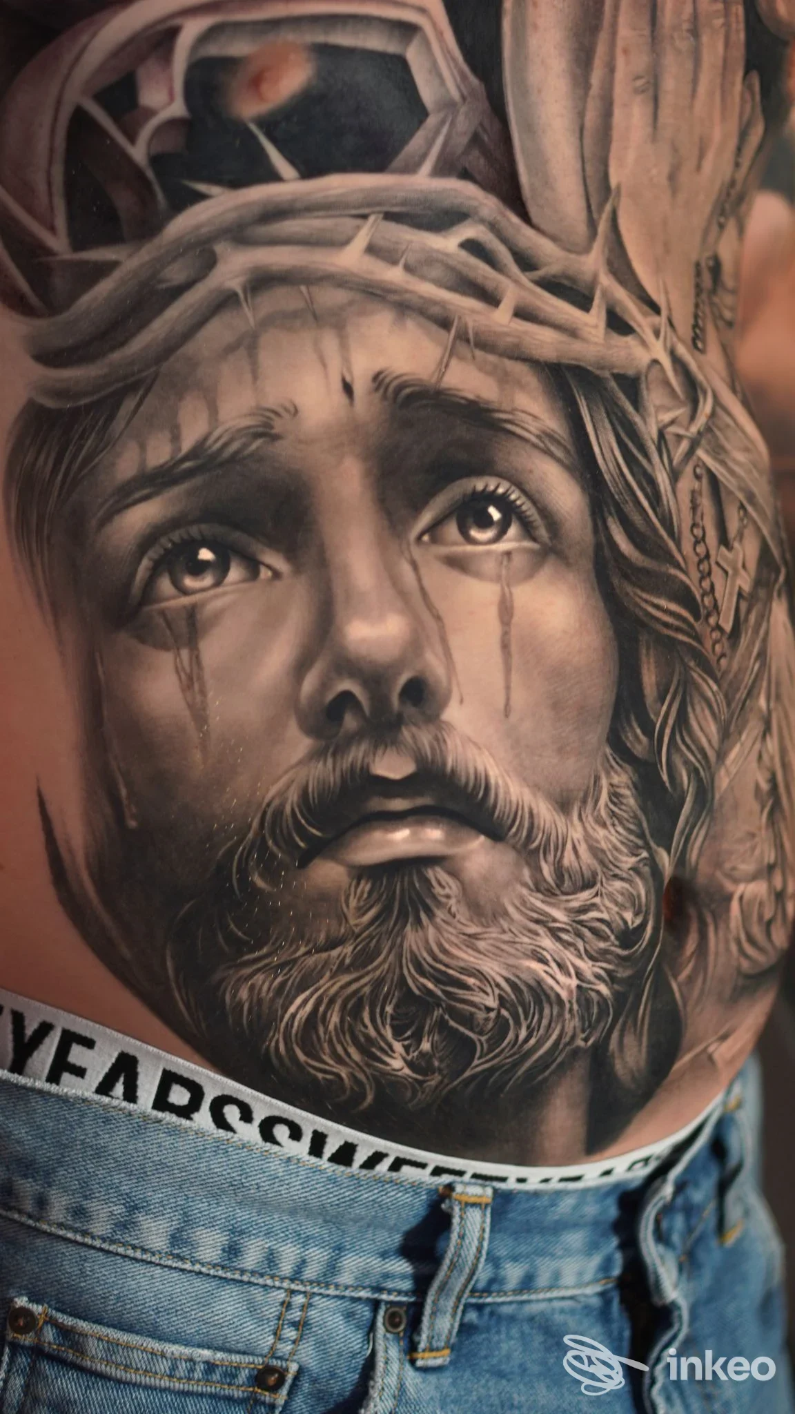 Tatuaggio realistico a tema religioso sul torso, foto inviata da Z Tattoo Shop a Bari.