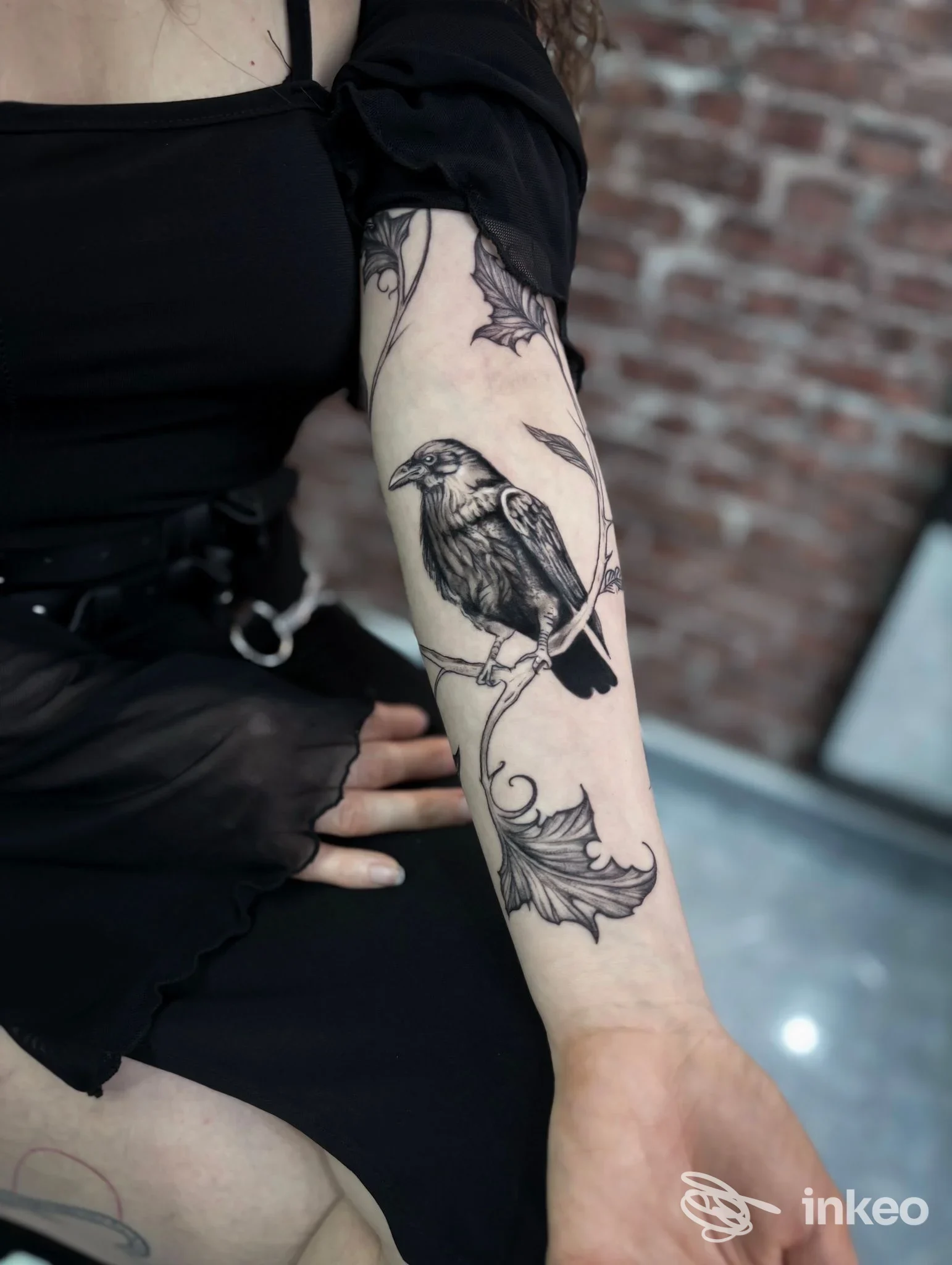 Avambraccio con tatuaggio di corvo e foglie in nero e grigio, dettagli nitidi. Foto per Miry Ink Tattoo Studio, Casavatore.