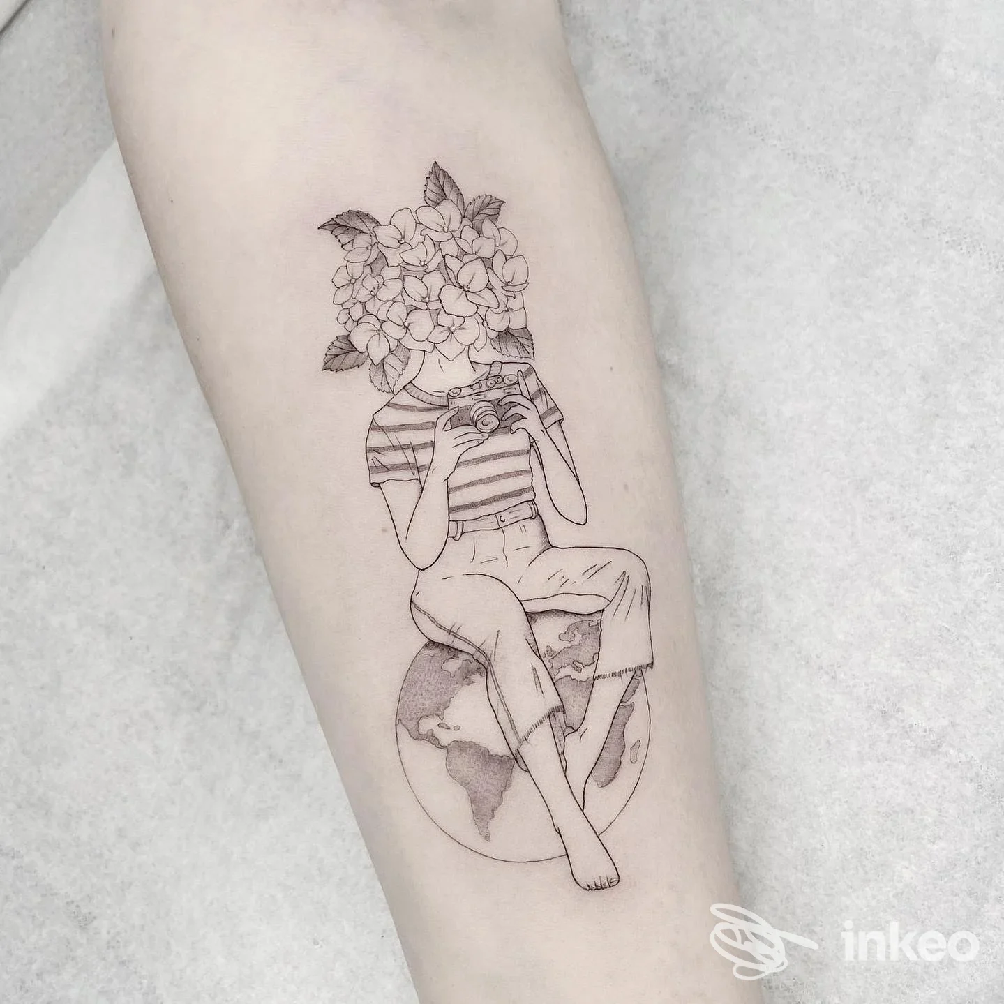 Tatuaggio in stile linework su avambraccio: figura con testa di fiori seduta su un mappamondo, Blind Garden Studio Ravenna.
