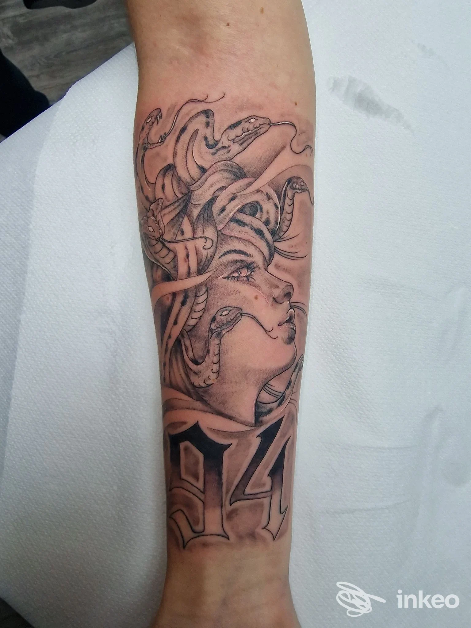 Tatuaggio black & grey su avambraccio raffigurante Medusa con serpenti e il numero 94 — Diamond & Stars Tattoo, Alessandria.