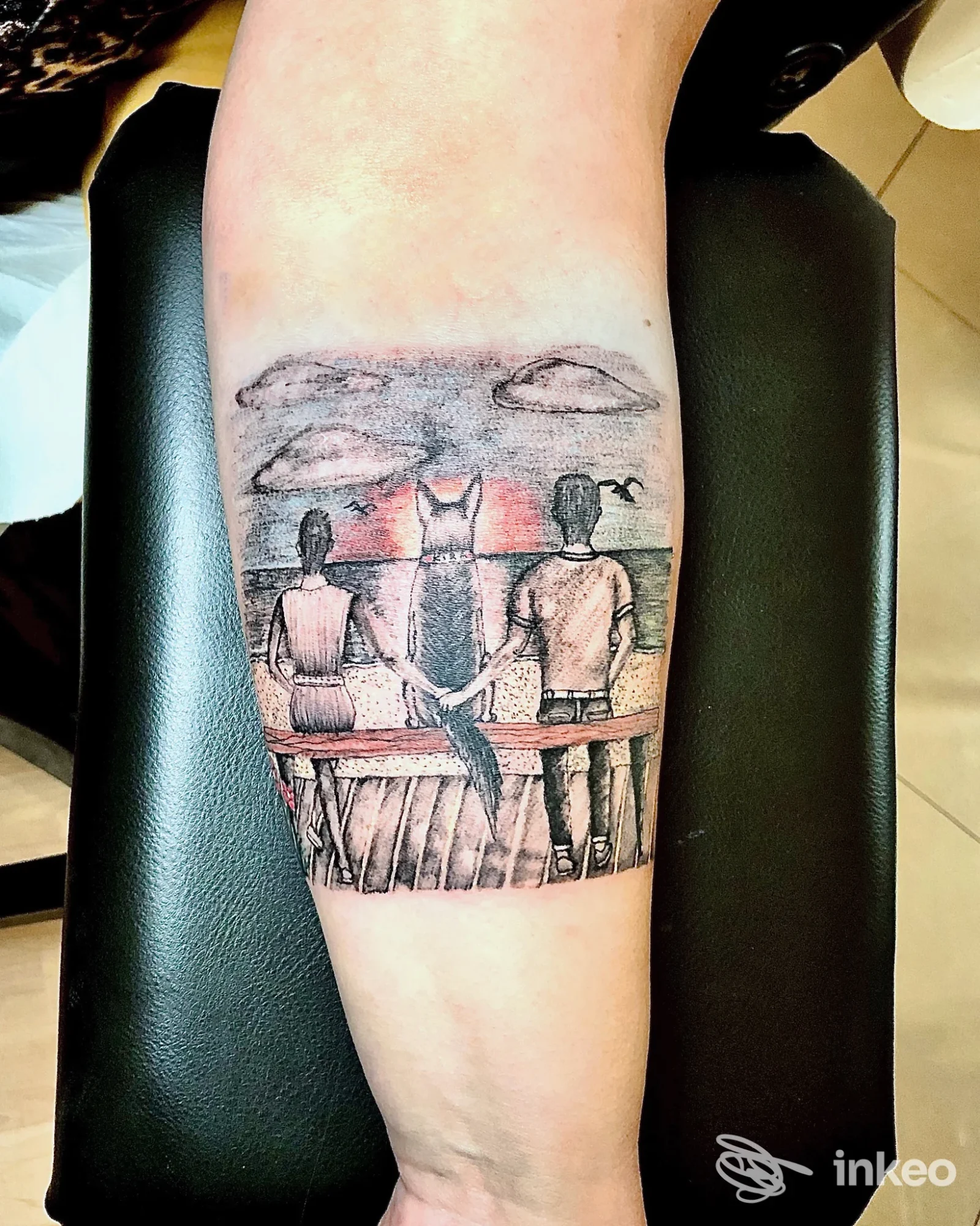 Tatuaggio su avambraccio con scena di tre figure che guardano un tramonto; immagine fornita da Endo Tattoo, Bari.