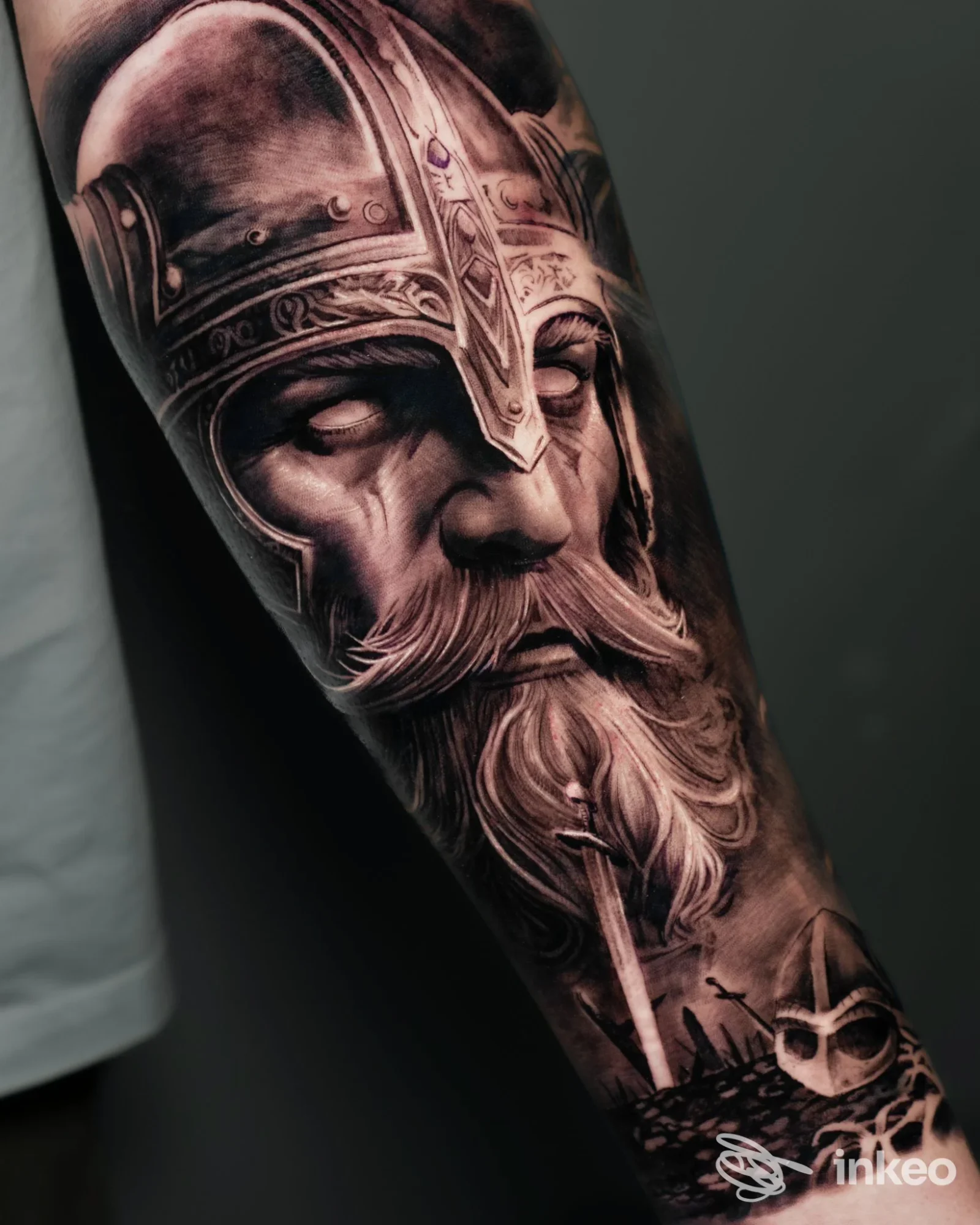 Ampio tatuaggio realistico in bianco e nero su avambraccio con volto barbuto e elmo, opera presentata da Red Ink Tattoo studio a Lariano.