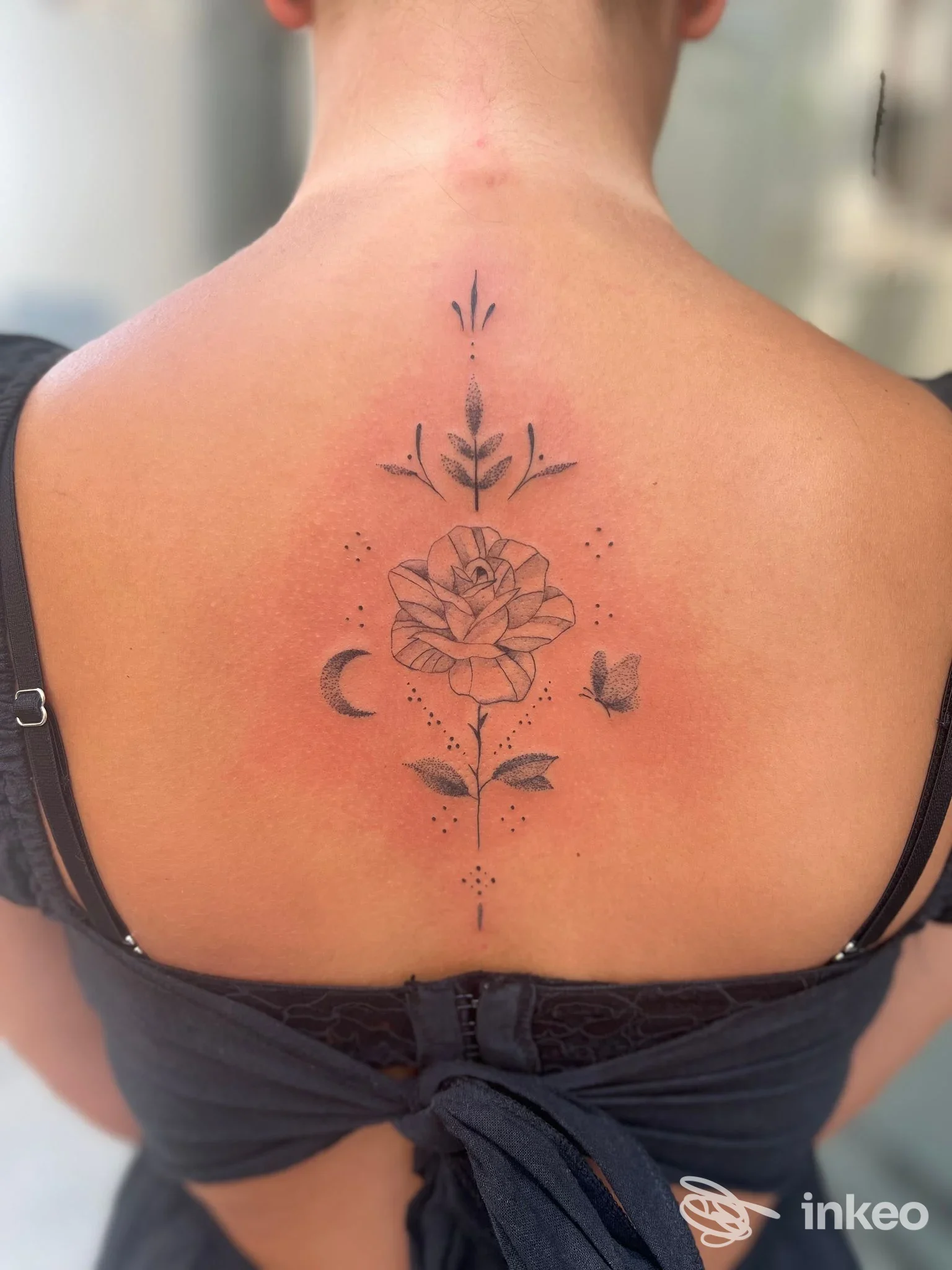 Tatuaggio floreale in blackwork con farfalla e mezzaluna al centro della schiena, foto fornita da MEMM INK, Venosa.