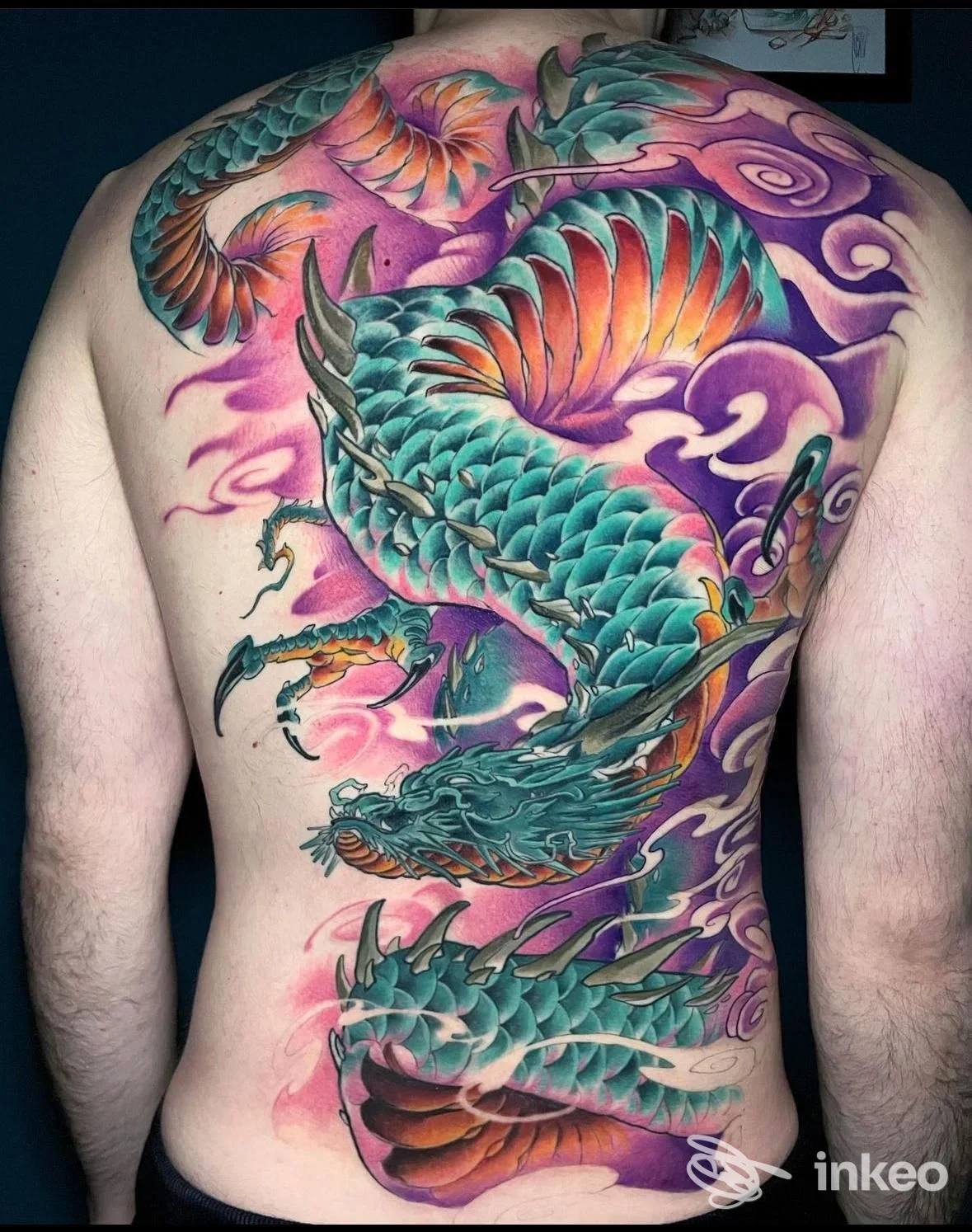 Grande tattoo colorato su schiena intera raffigurante un drago stilizzato con scaglie azzurre e sfumature rosa e arancione, senza viso visibile.