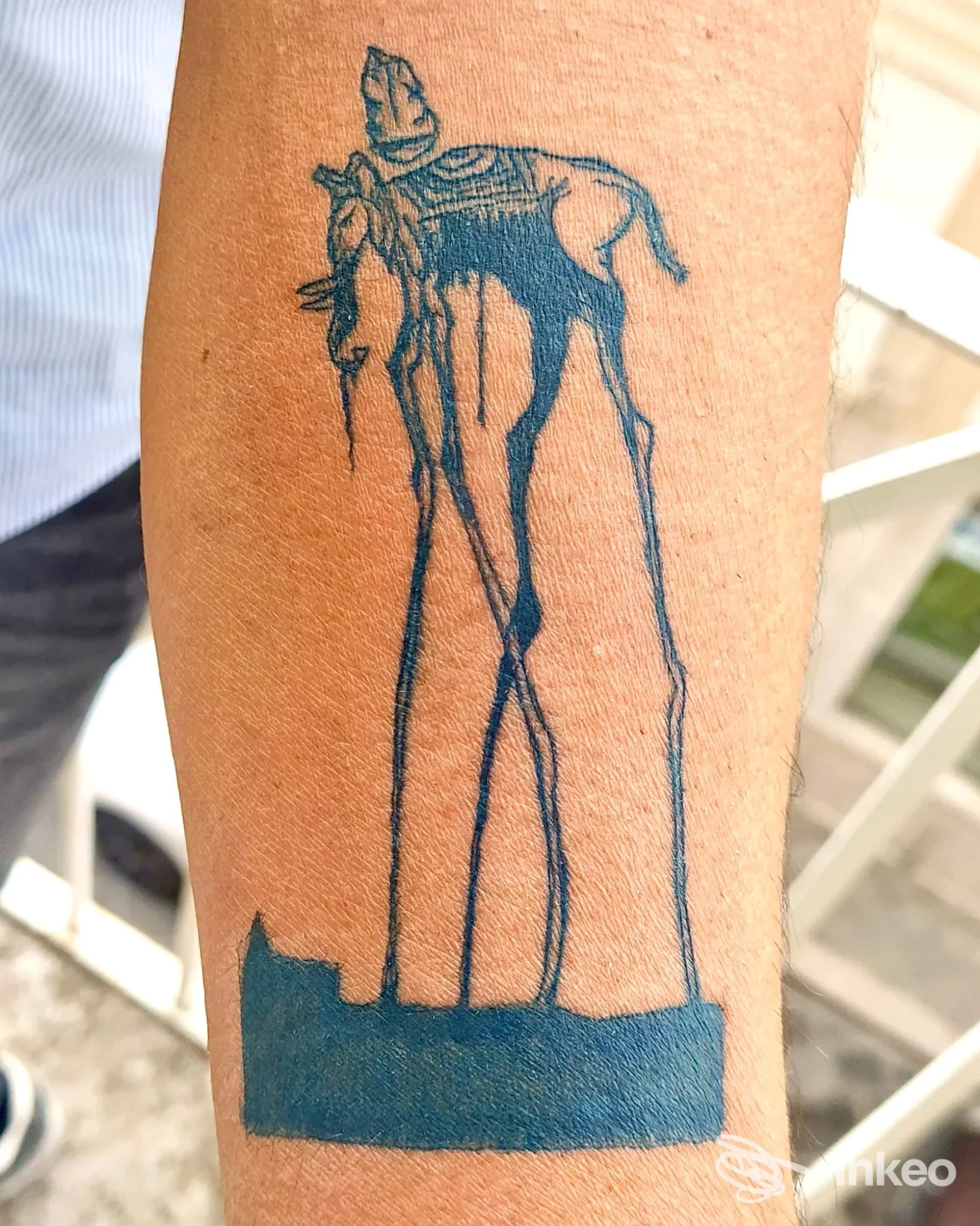 Tatuaggio blu-nero su avambraccio raffigurante figura stilizzata; Iron Mallet Tattoo Parlour, Corato.