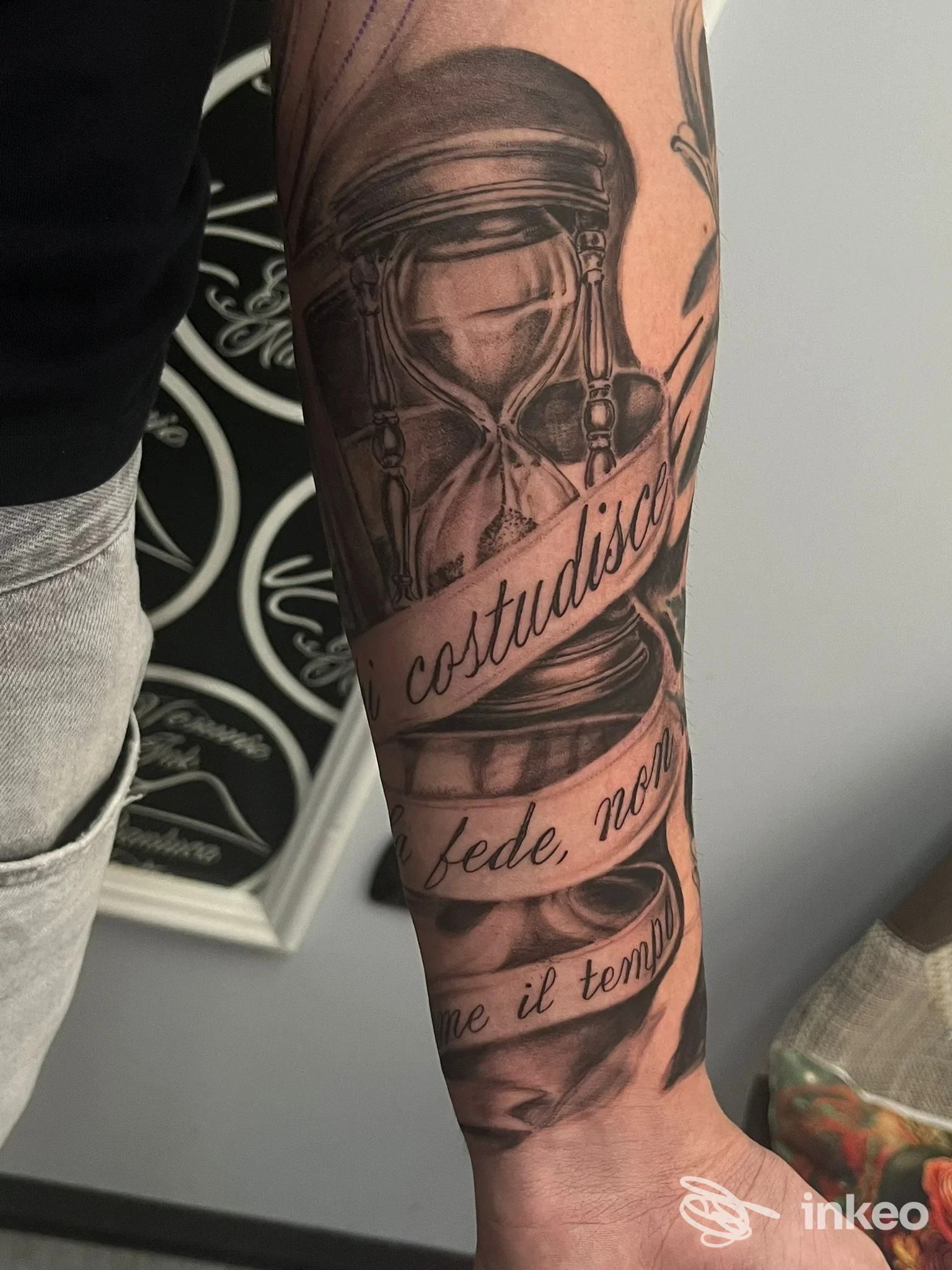 Tatuaggio a clessidra e nastro con scritte in corsivo sull'avambraccio, foto fornita da Vesuvio Ink tattoo studio, Marigliano.