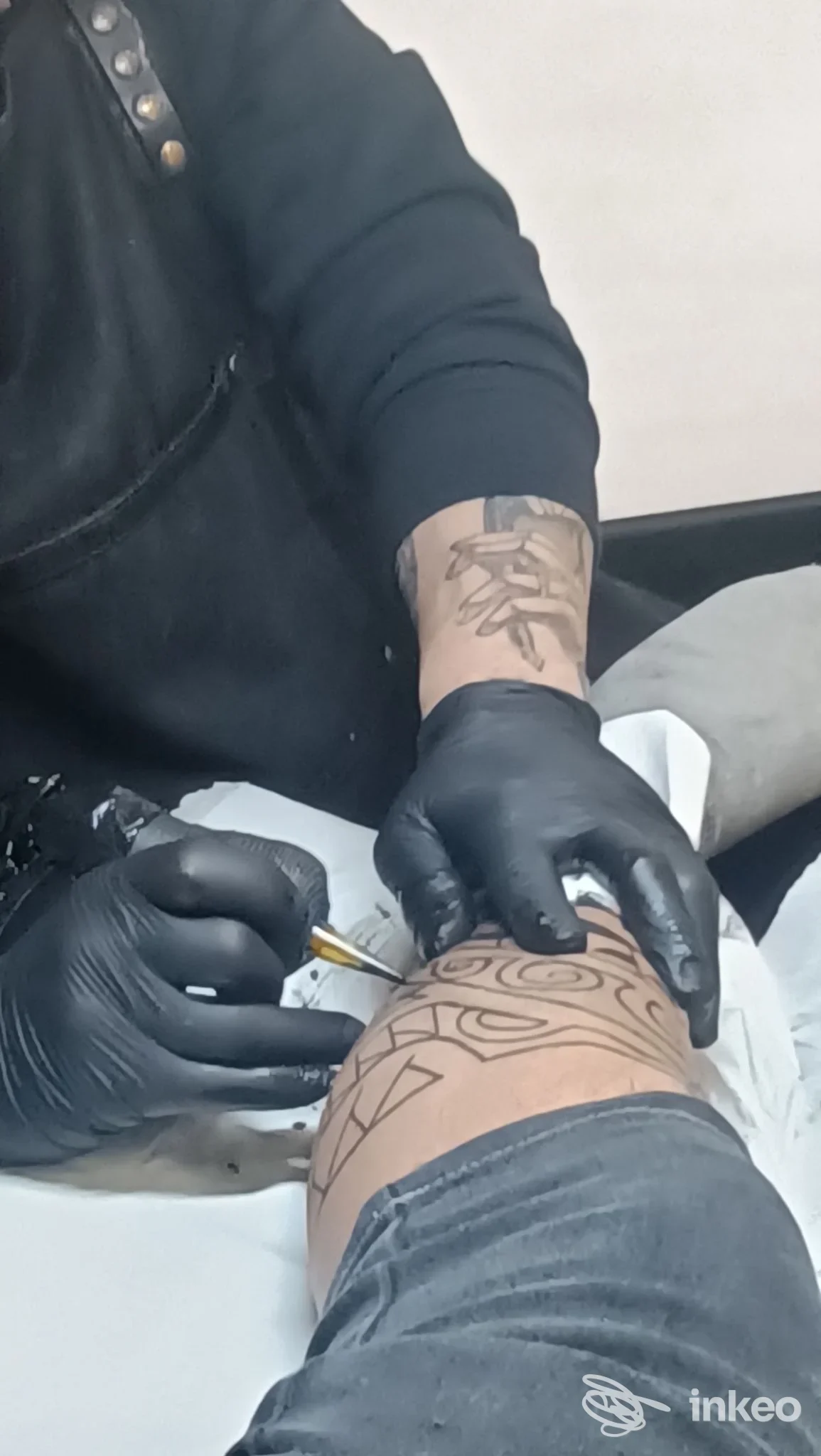 Tatuatore al lavoro su disegno geometrico in nero sulla parte inferiore della gamba, Sick To Ink, Palermo.