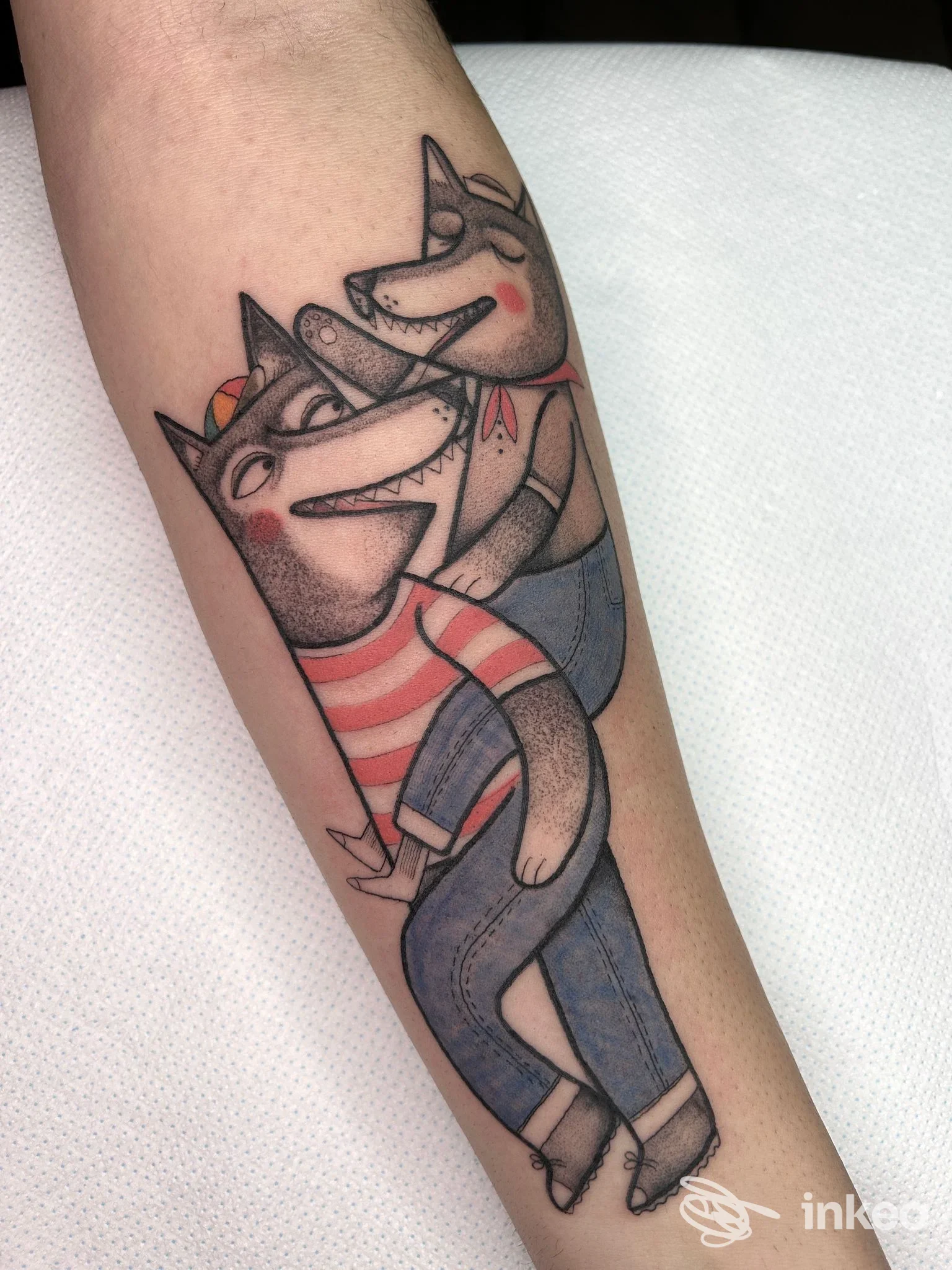 Tatuaggio sull'avambraccio di due volpi/lupi stilizzati, colori rosa, blu e nero — immagine fornita da Studio Matita Tattoo, Bergamo.