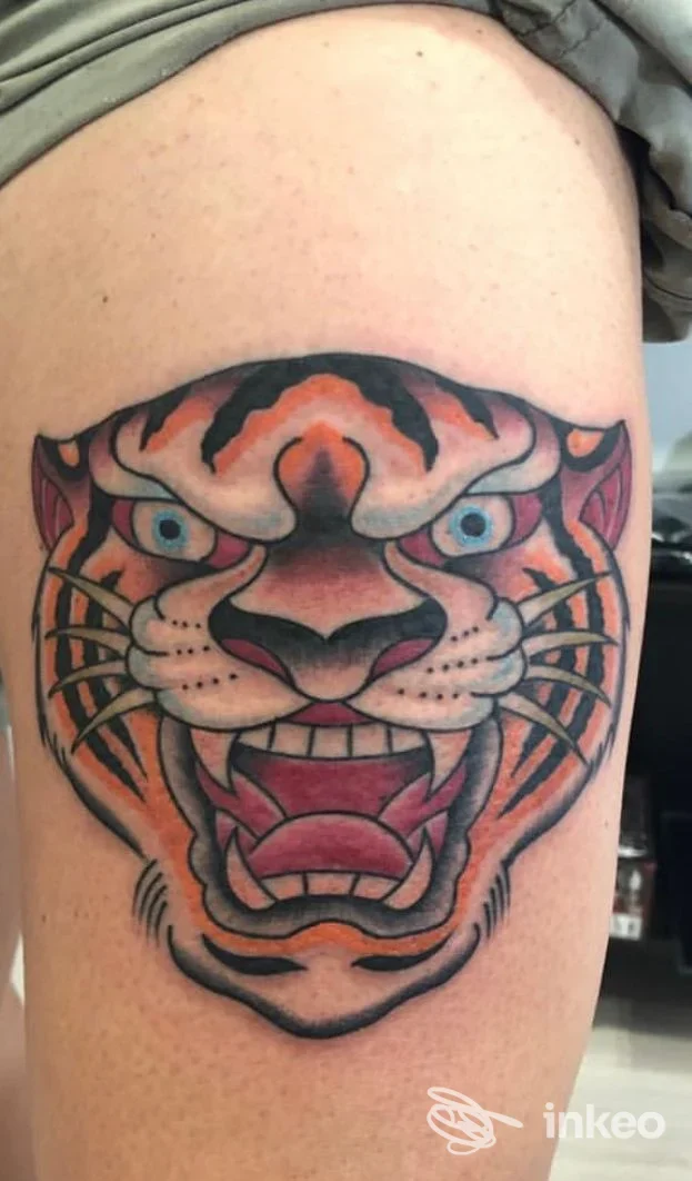 Tattoo tiger su pelle di coscia, colori vividi, linea nera netta, inquadratura singola.