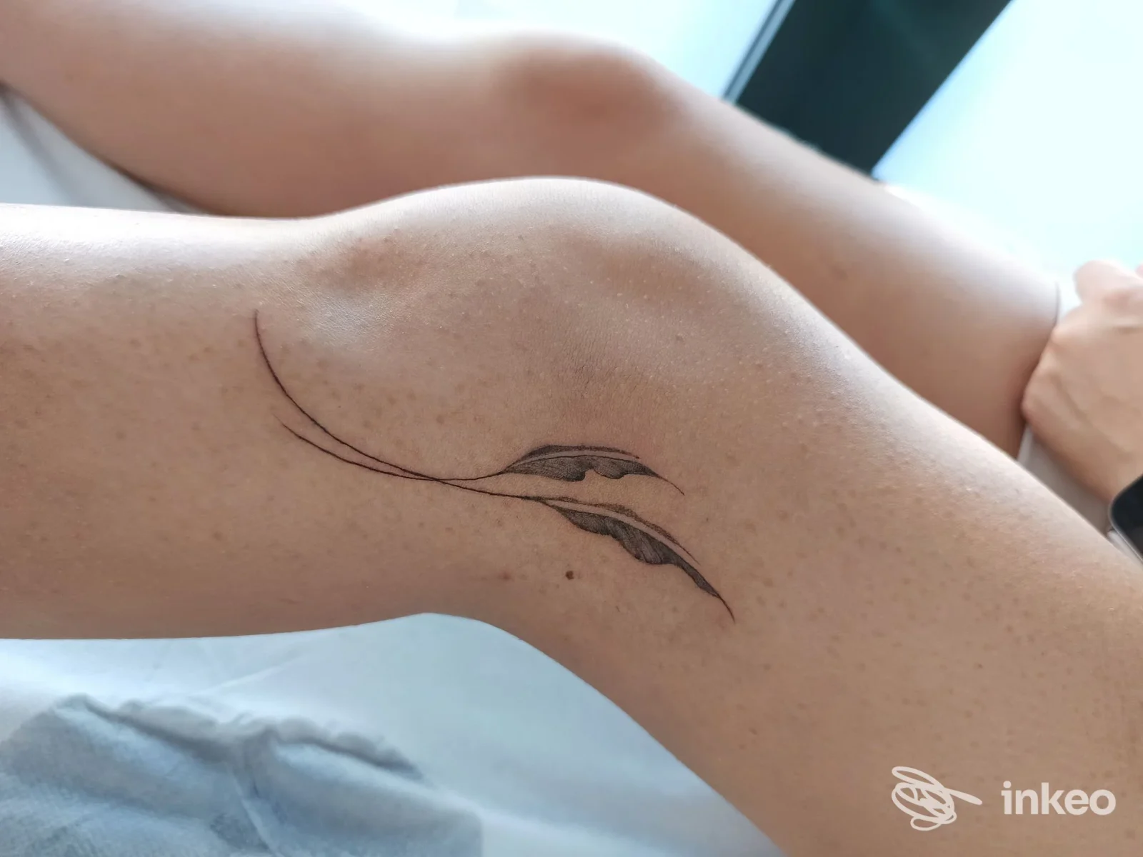 Tatuaggio minimalista lineare su pelle della gamba, con due linee curve che formano un motivo astratto. Studio Good Ink Tattoo, città non specificata.
