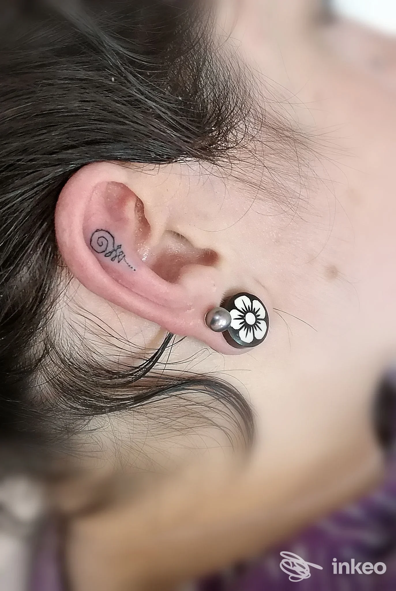 Primo piano dell'orecchio con piccolo tatuaggio vicino al lobo e plug decorativo — Beauty & the Beast Tattoo Studio, Mondovì.