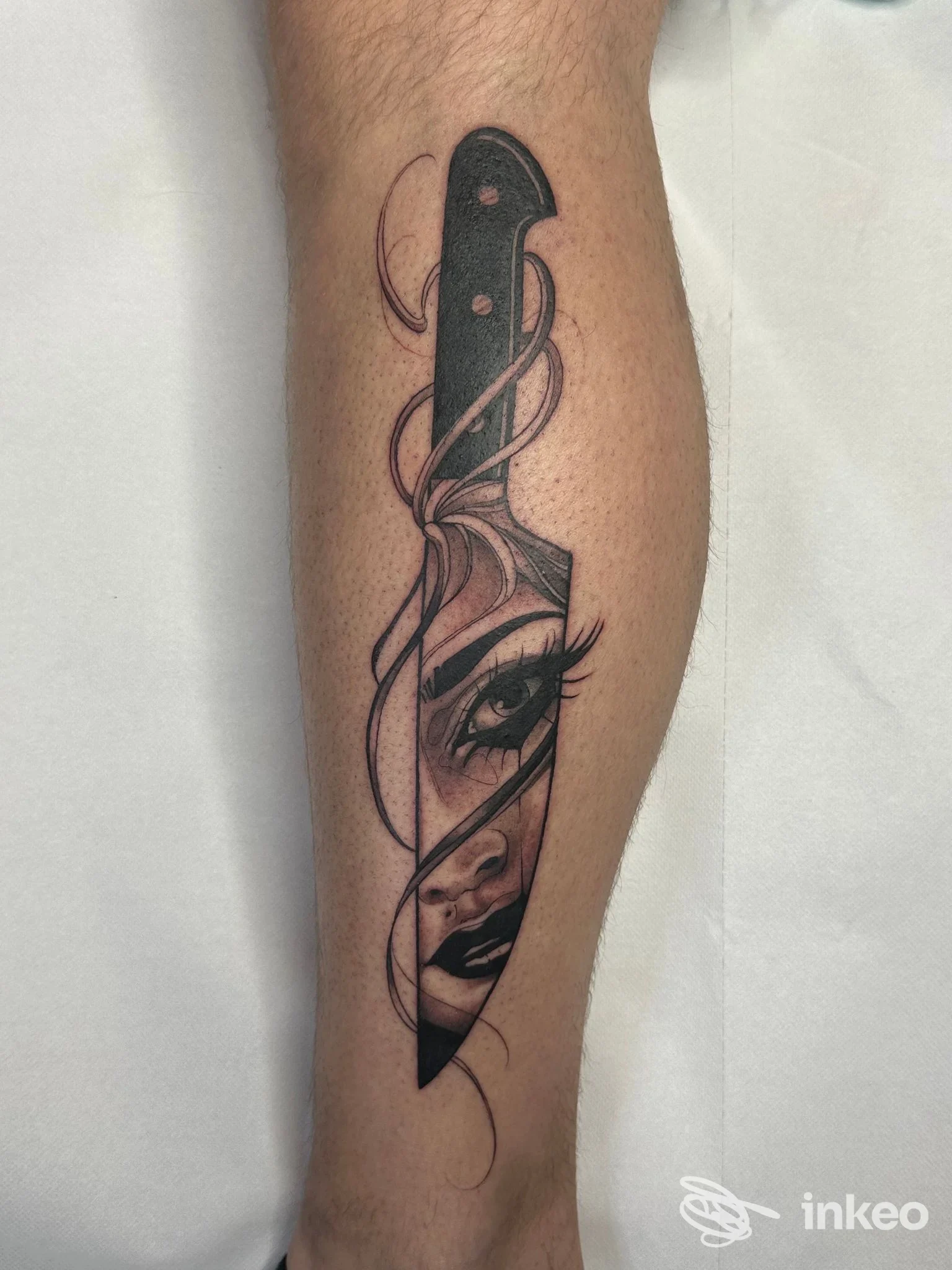 Tatuaggio su polpaccio: coltello con volto femminile integrato, eseguito da ALEX DE PASE STORES, Udine.