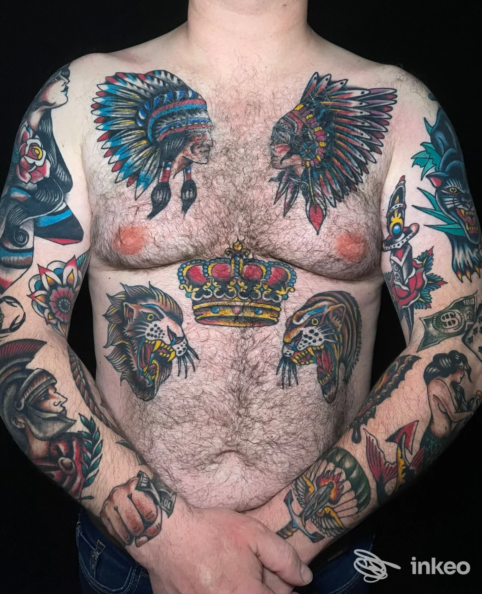 Torso tatuato con copricapi piumati sul petto, corona sotto lo sterno e teste di felini sull'addome — Bassetti Tattoo e Piercing, Roma.