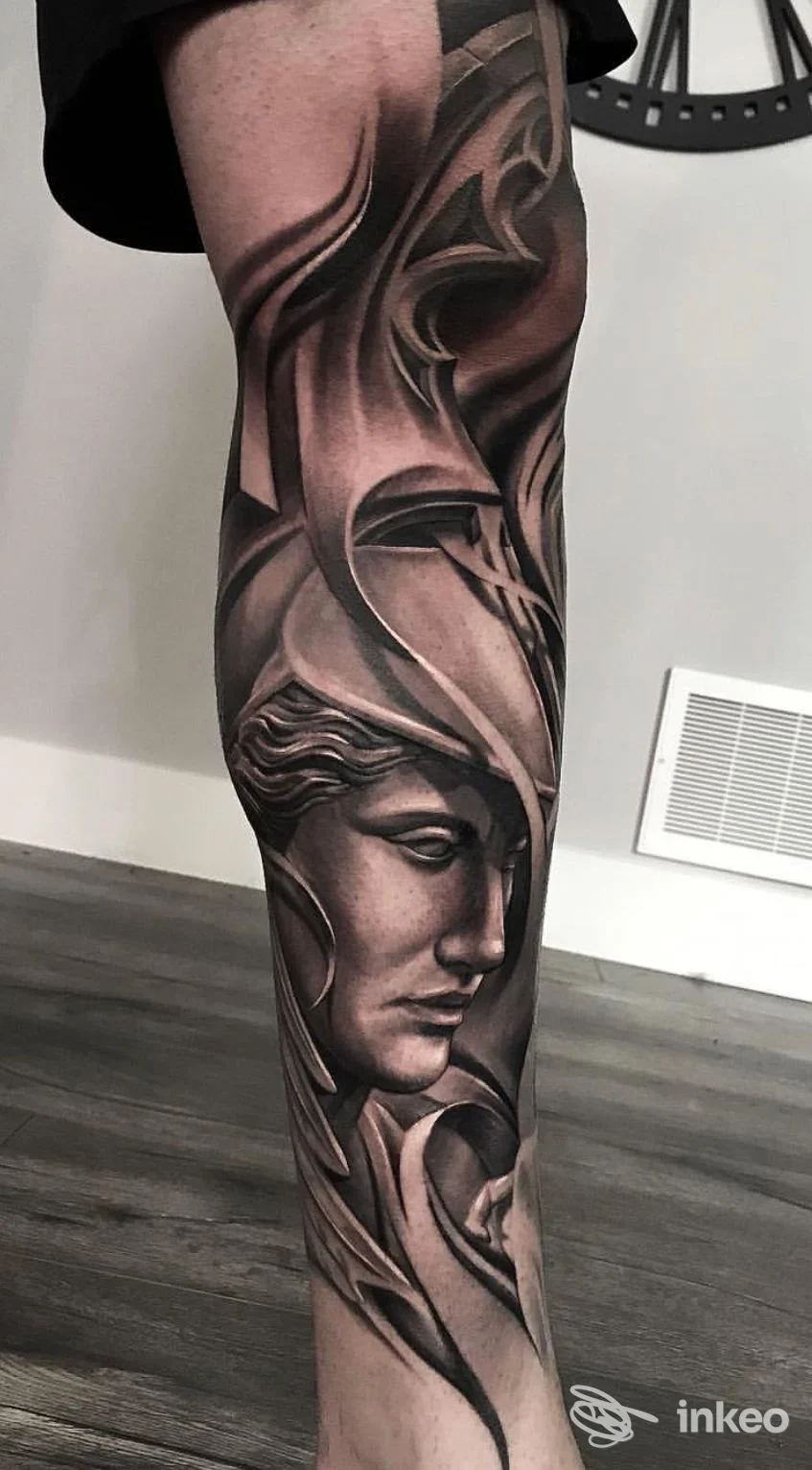 Tatuaggio realistico black & grey su gamba, volto stilizzato e decorazioni — Studio Tatuaggi, Medesano.
