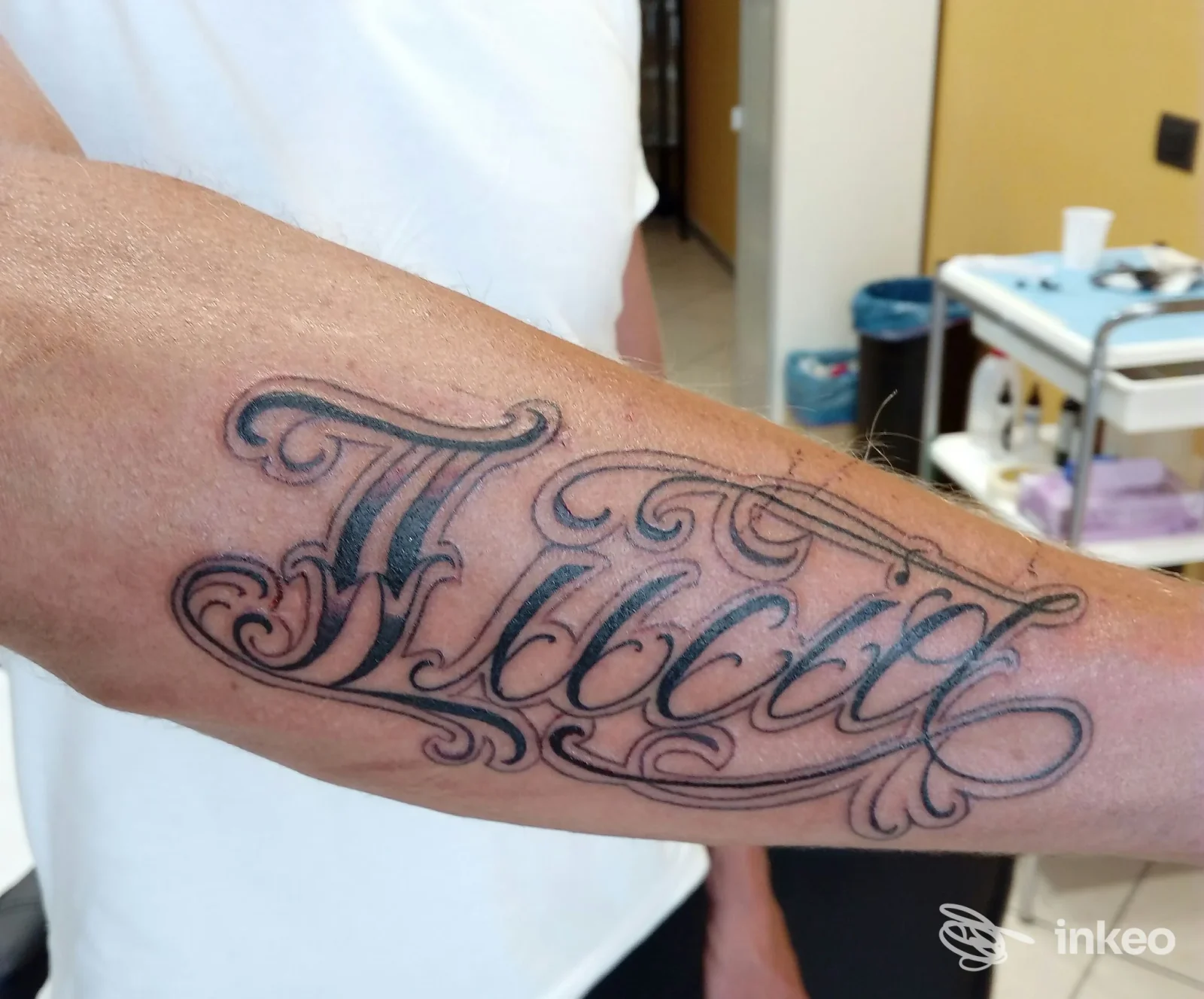 Tatuaggio lettering nero sull'avambraccio fotografato all'interno di Borneoflower Piercing Studio, Sanremo.