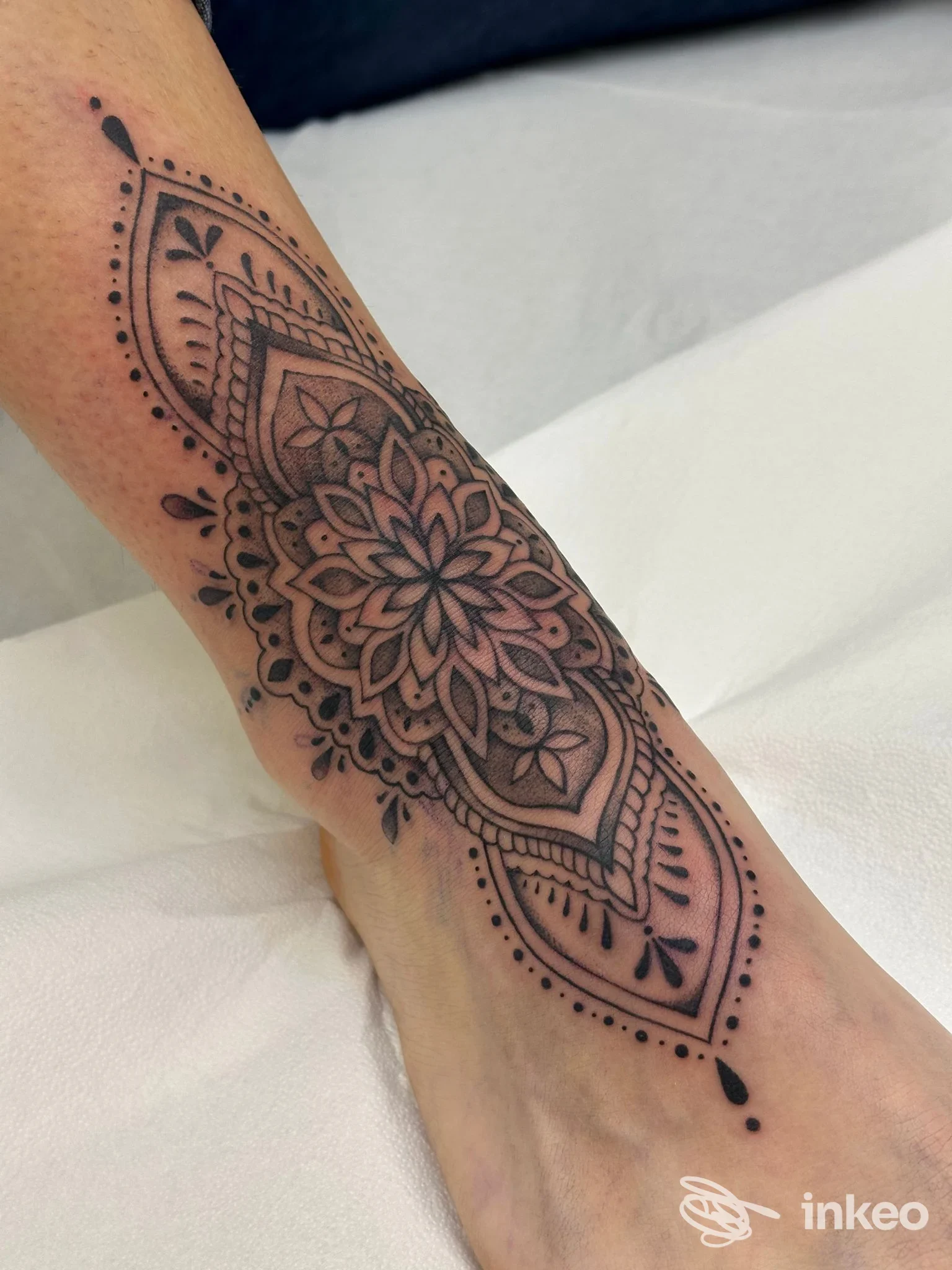 Tatuaggio mandala nero sull'avampiede e caviglia, fotografia di Baltica Tattoo a Roma che mostra il lavoro su pelle reale.