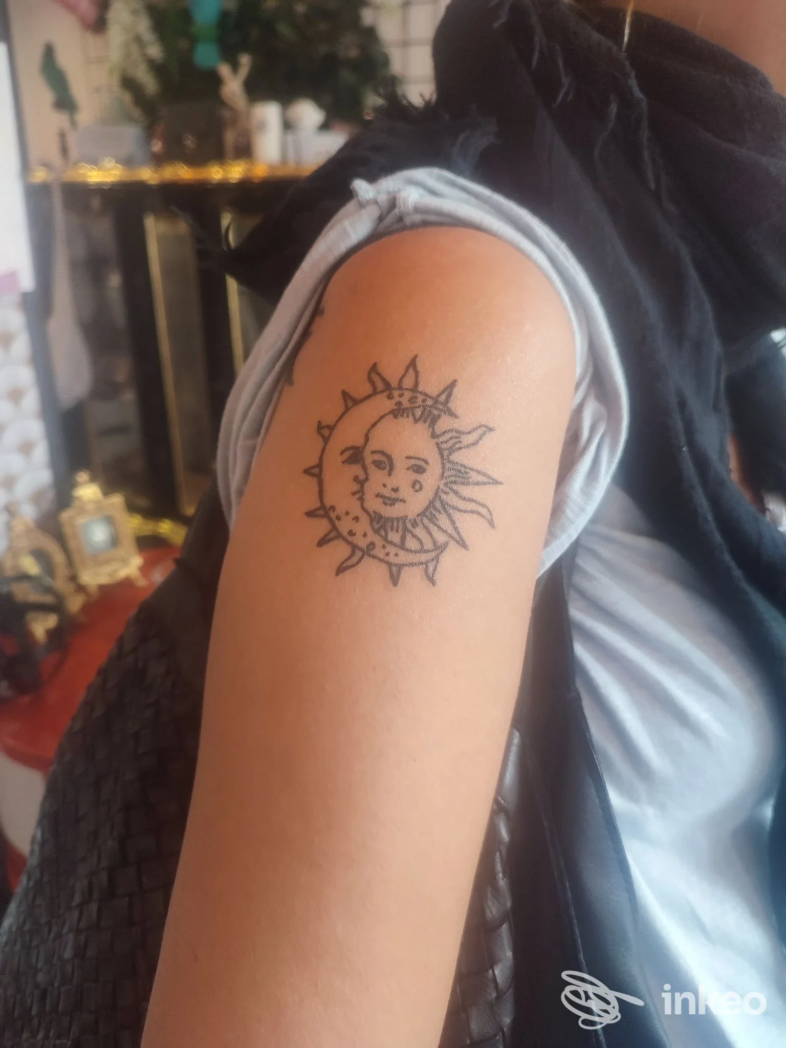 Tatuaggio stilizzato di sole e luna sul braccio superiore, realizzato presso Mamyink Tattoo a Bordighera.