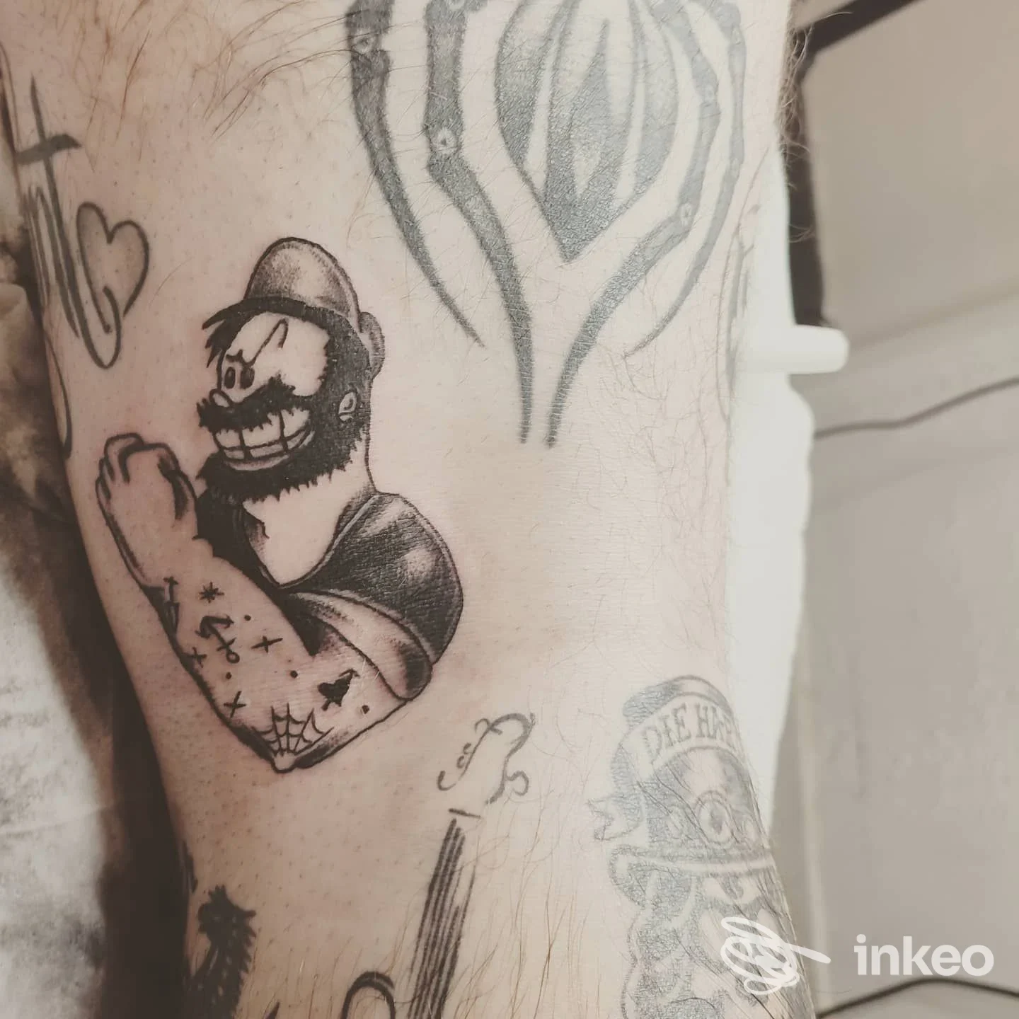 Primo piano di un tatuaggio su braccio con figura in stile cartoon; immagine fornita da Mamyink Tattoo Piercing a Bordighera.