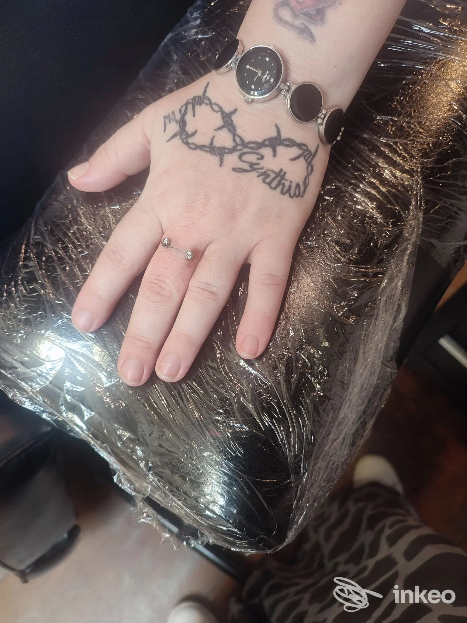 Primo piano di una mano tatuata con filo spinato e scritta, foto fornita dallo studio Mamyink Tattoo Piercing a Bordighera.