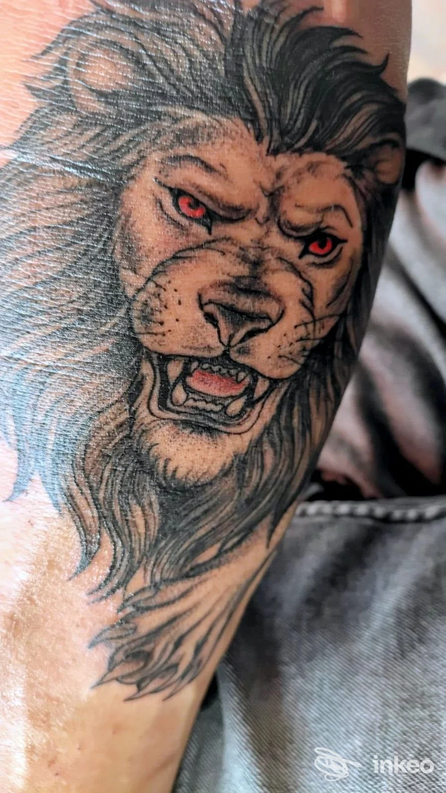Tatuaggio su avambraccio di un leone ruggente con occhi rossi, immagine da Body Art Piercing E Tattoo, Cassino.