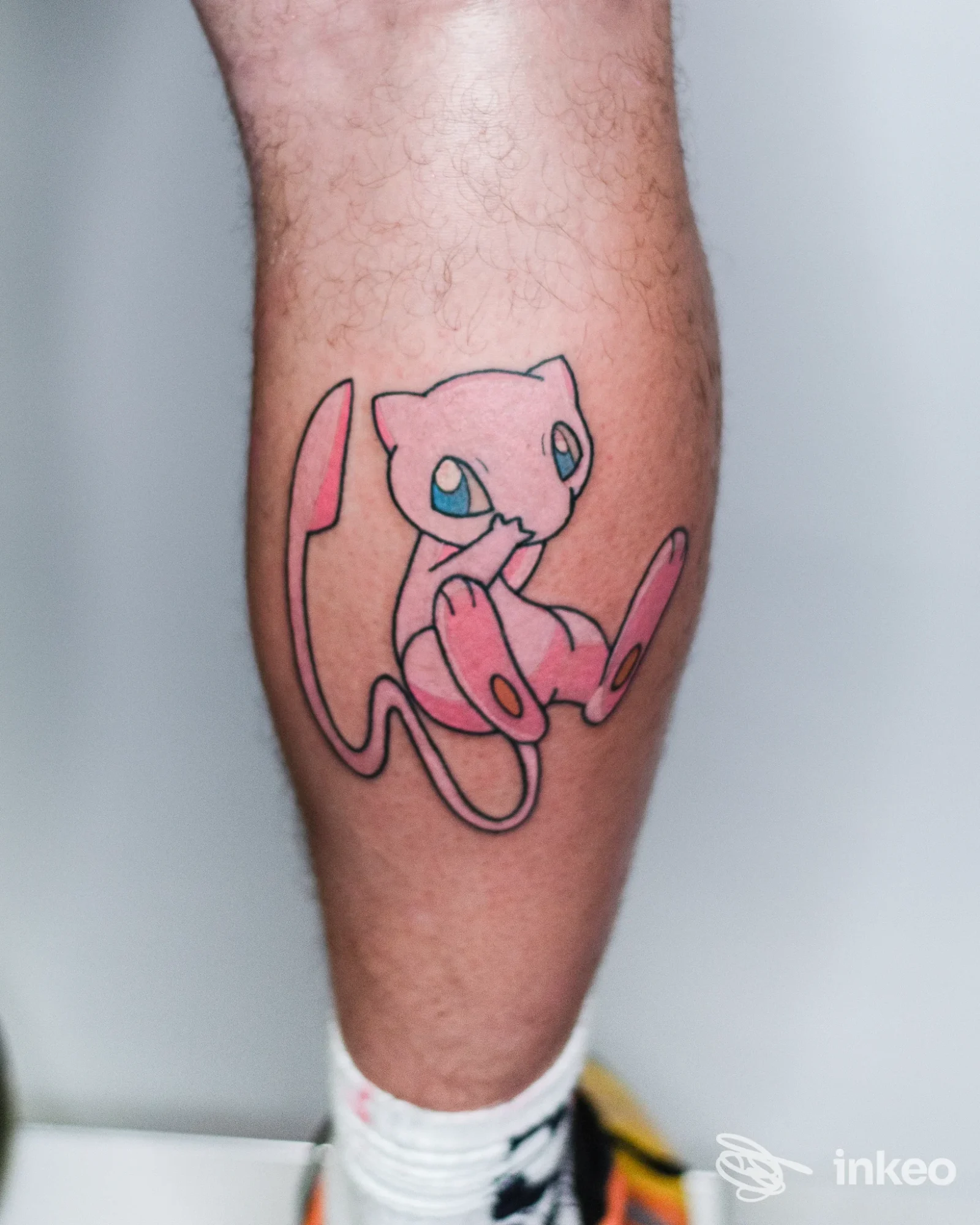 Tatuaggio su polpaccio raffigurante Mew realizzato dallo studio True Love a Savona, dettaglio su pelle con contorni neri e riempimento rosa.