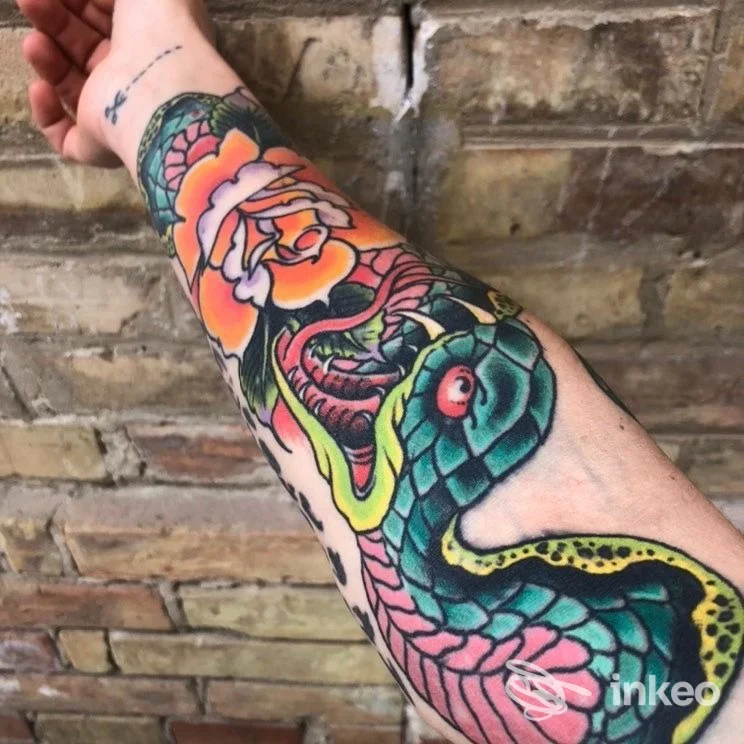 Avambraccio tatuato con serpente colorato e rosa arancio, foto fornita da The Grim Reaper Tattoo, Roma.
