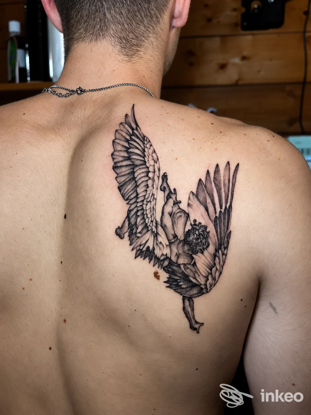 Tatuaggio a inchiostro scuro di un uccello in volo sulla scapola destra, foto fornita da INK ATELIER Tattoo & Piercing, La Spezia.