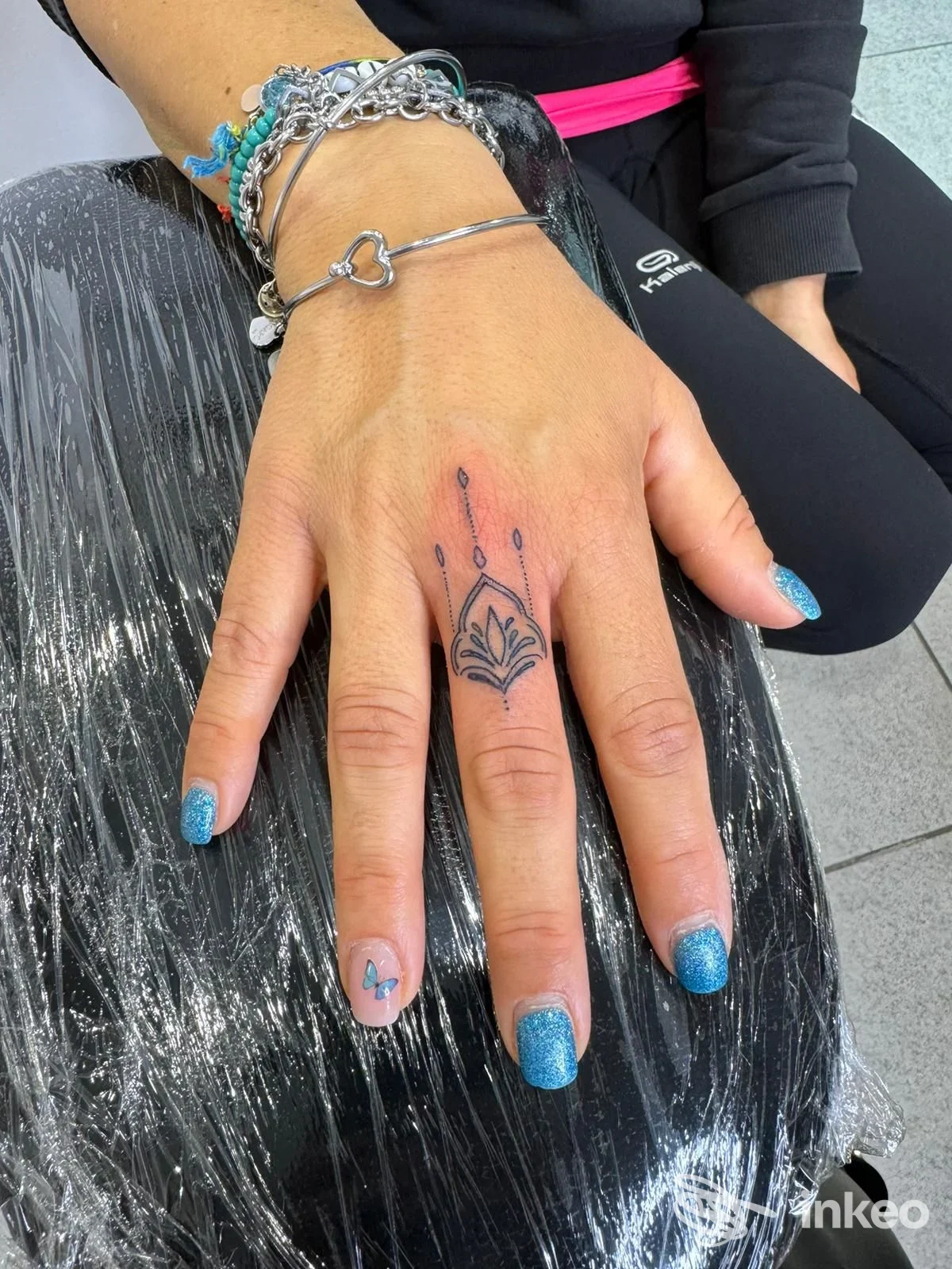 Primo piano di una mano con piccolo tatuaggio ornamentale sul dito medio, scattato da Artemis Beauty Tattoo Studio a Cuneo.