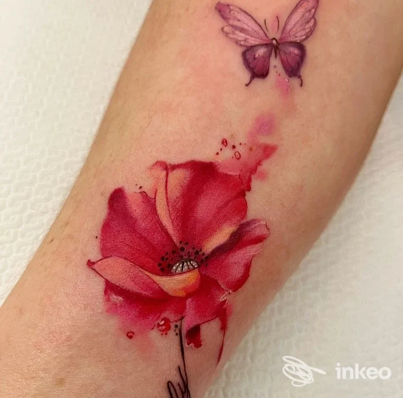 Tatuaggio acquerellato di un fiore rosso con piccola farfalla violacea sull'avambraccio, realizzato da Bohemia Body Art a Galatina.
