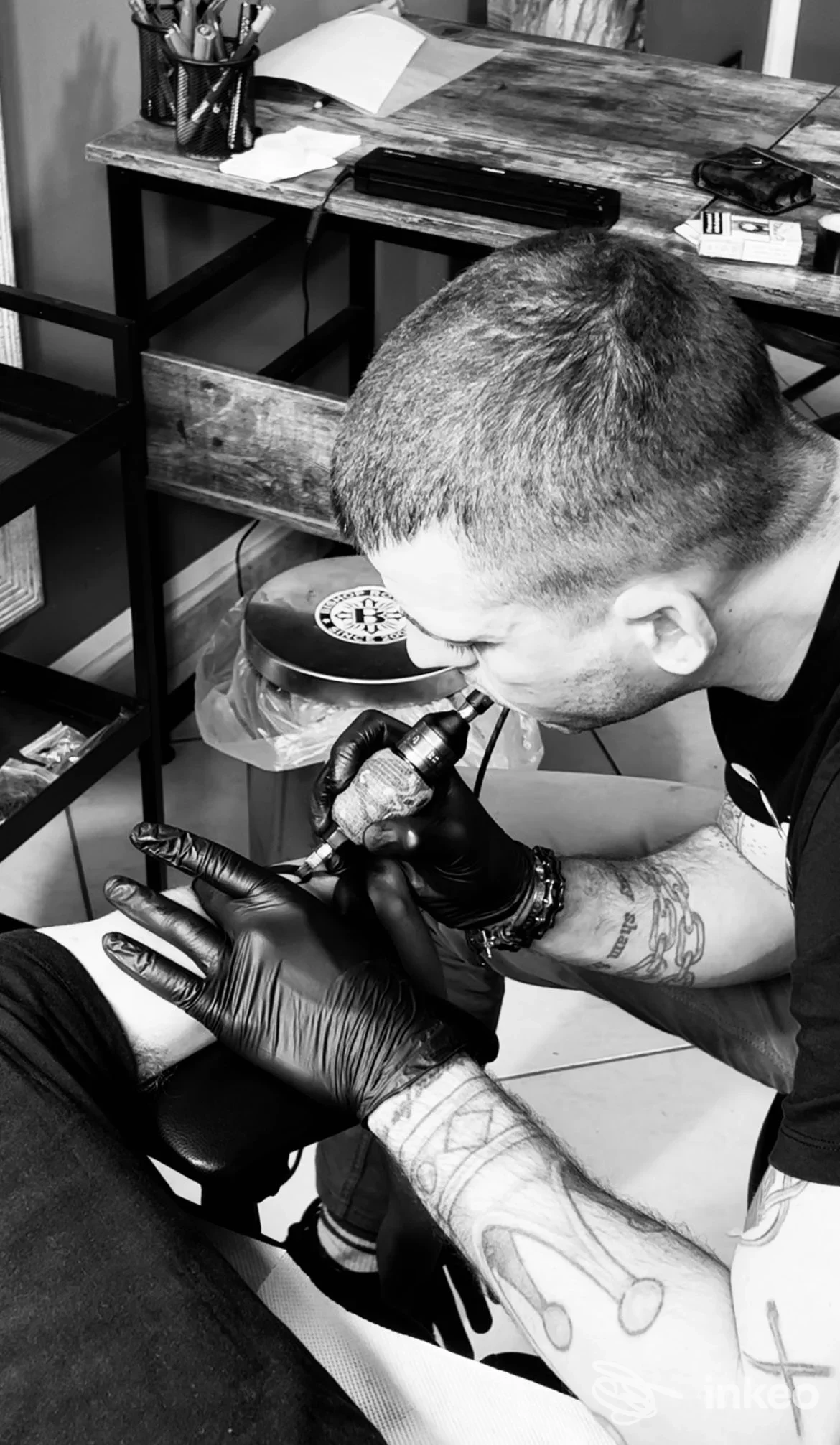 Tatuatore al lavoro nello studio CB Custom Tattoo, macchina da tatuaggio su un arto inferiore durante una sessione.