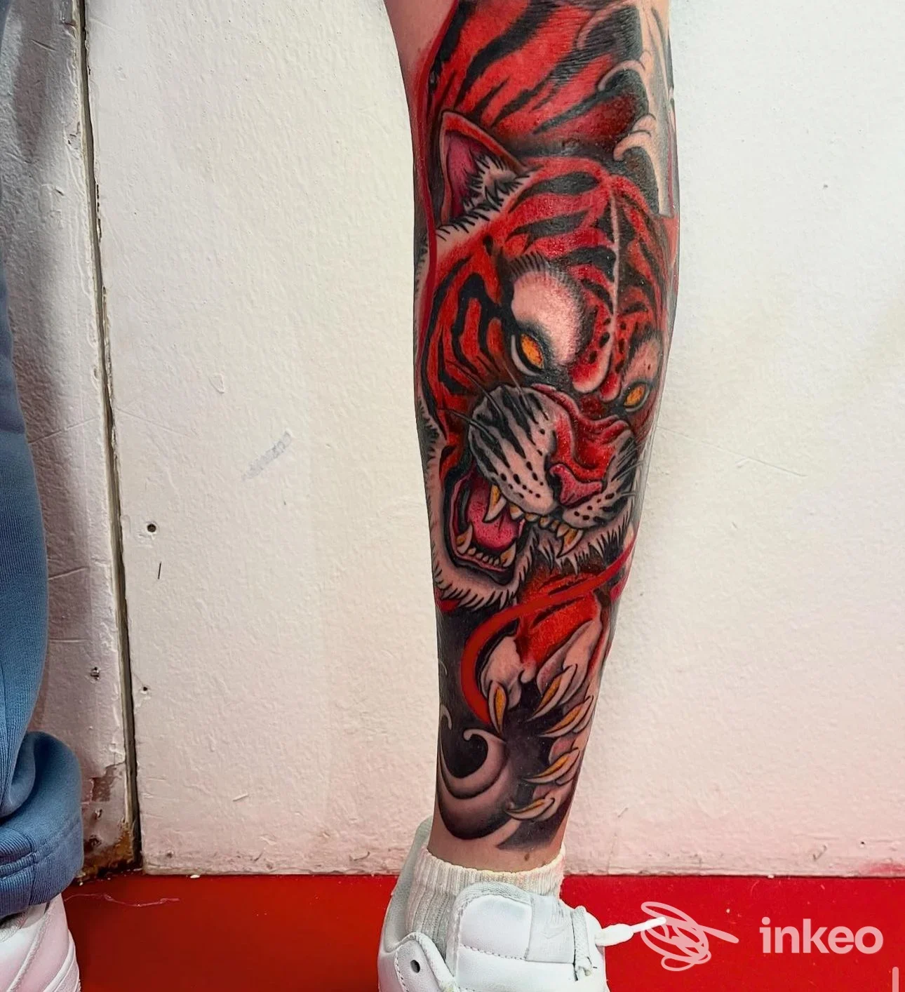 Fotografia di un tatuaggio a colori che raffigura una tigre aggressiva sul polpaccio destro; lavoro ben rifinito, realizzato da Inked Society - Tattoo & Piercing Studio a Melendugno.