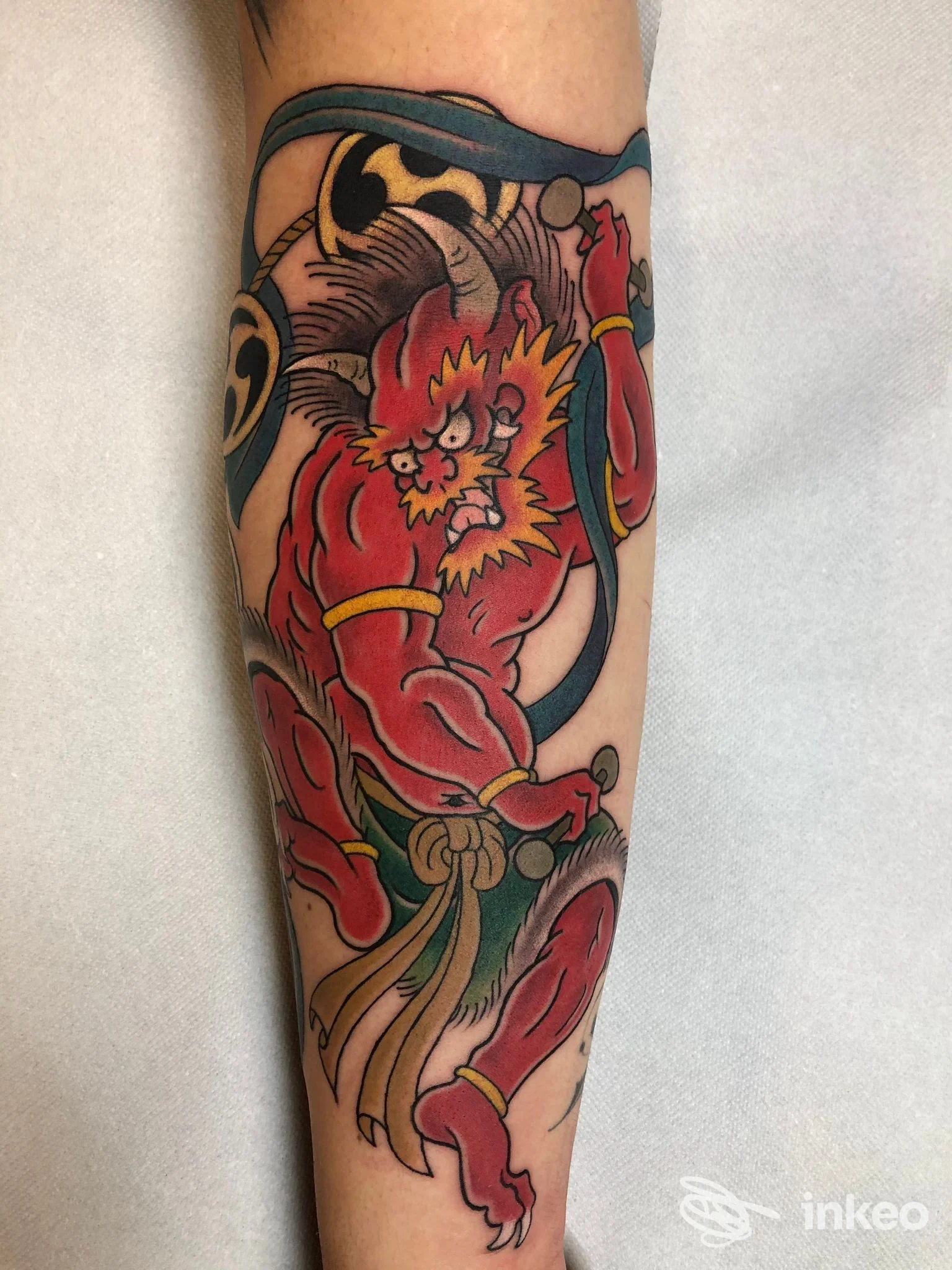 Primo piano di tatuaggio su avambraccio raffigurante un demone rosso, realizzato da inkiostro mancino a Camerata Picena.