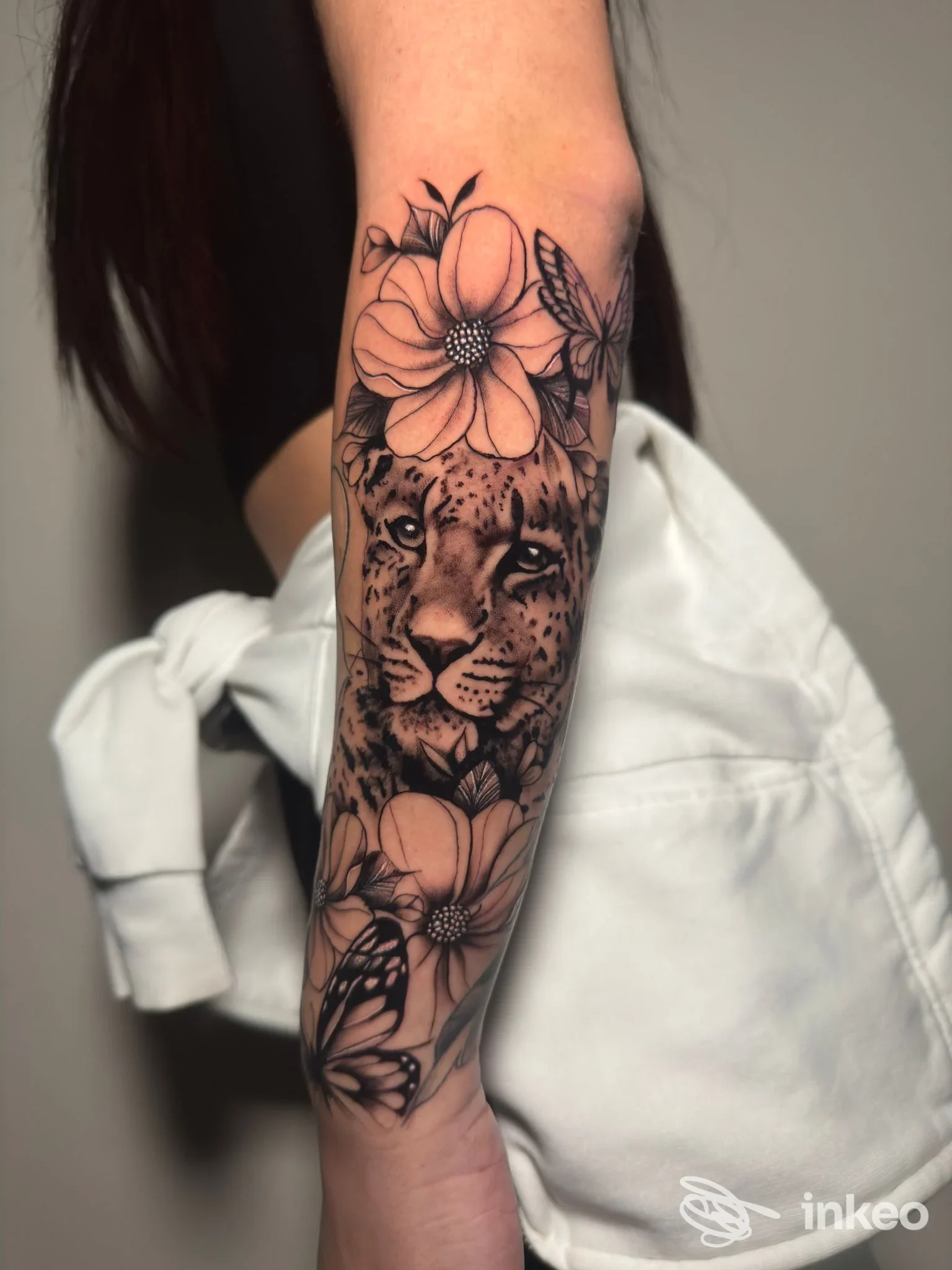 Tatuaggio realistico su avambraccio con volto di leopardo, fiori e farfalle, STORIE DI VITA SU PELLE, Fossano.