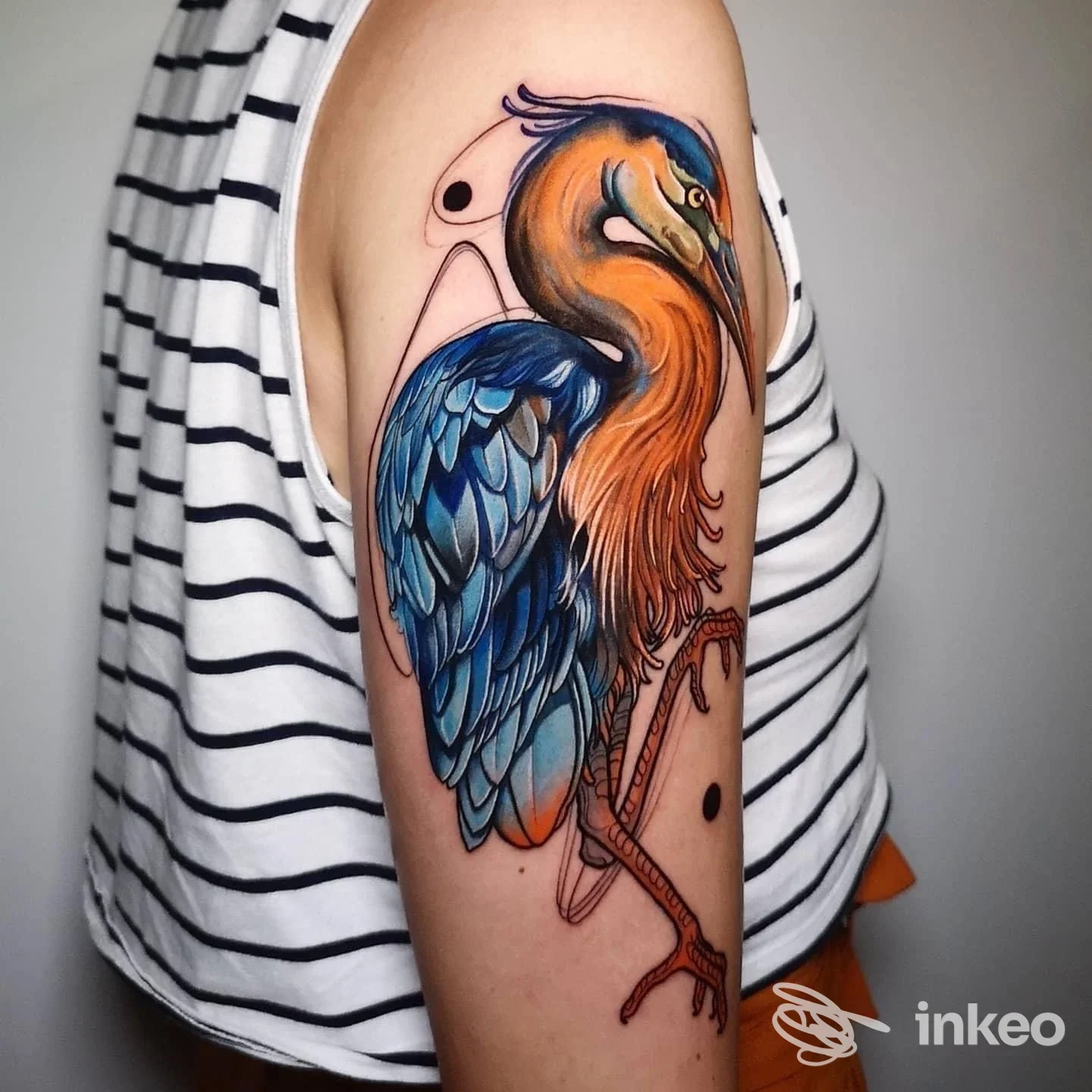 Tatuaggio colorato a forma di airone sull'area superiore del braccio, fotografato per LUMOS Tattoo Studio, Torino.