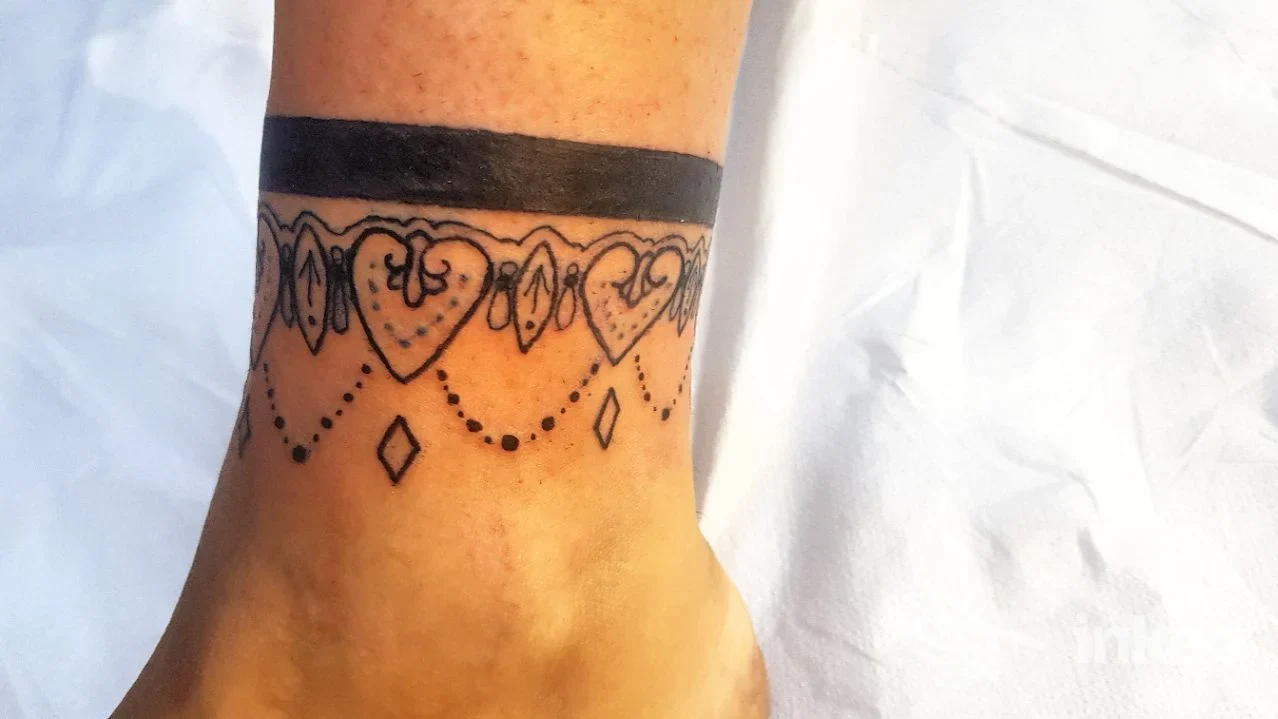 Tatuaggio a fascia con cuori e decorazioni sulla caviglia, fotografato per Tattoo Beauty Saloon a Condove.