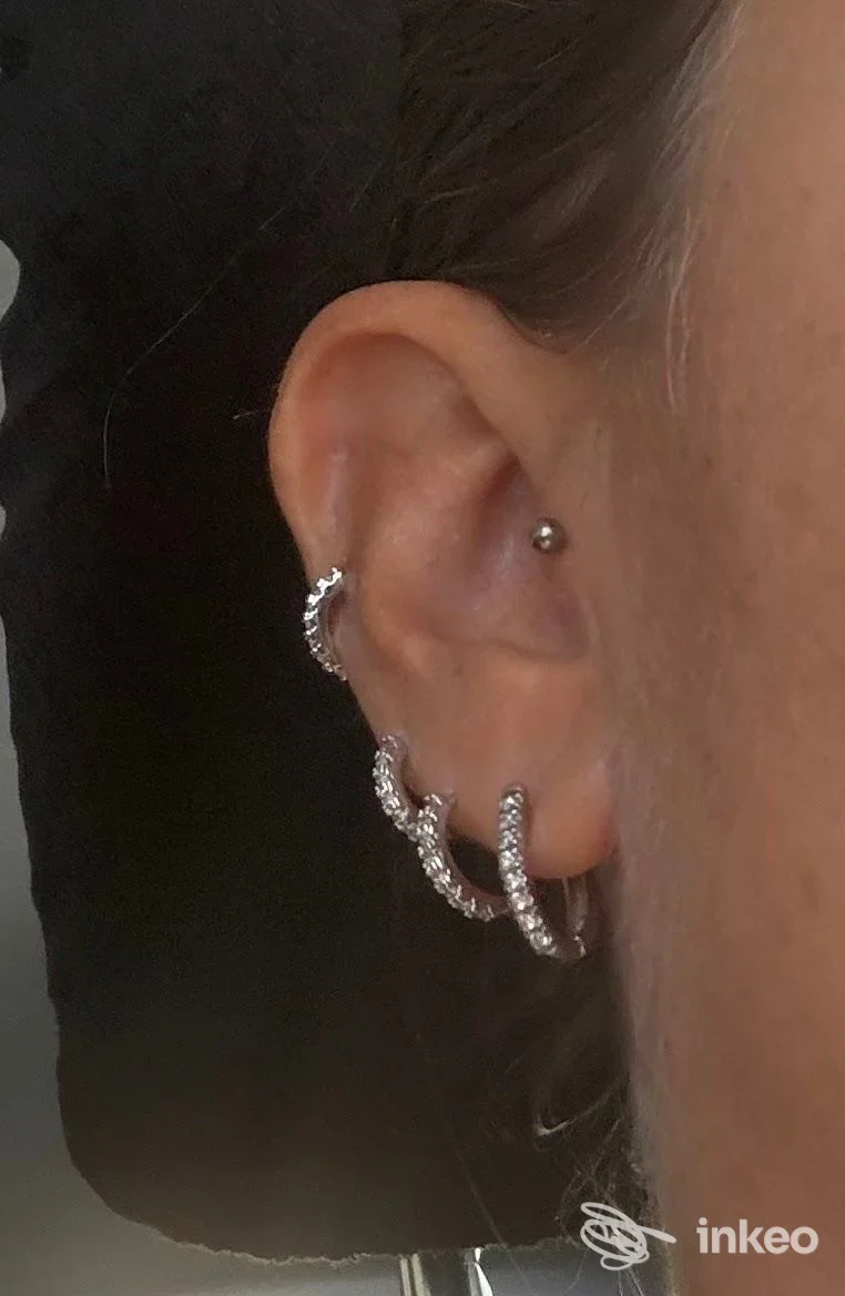 Foto di orecchio con tre cerchi brillanti e un piercing alla cartilagine, scattata per il laboratorio Lorenzo Agnelli a Torino.