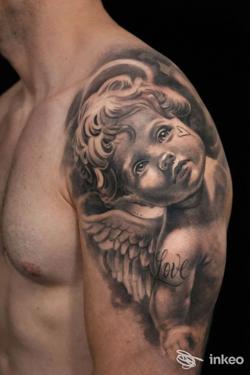 Tatuaggio realistico a spalla e braccio con putto angelico in bianco e nero, fotografato da Prestige Tattoo Studio, Ancona.