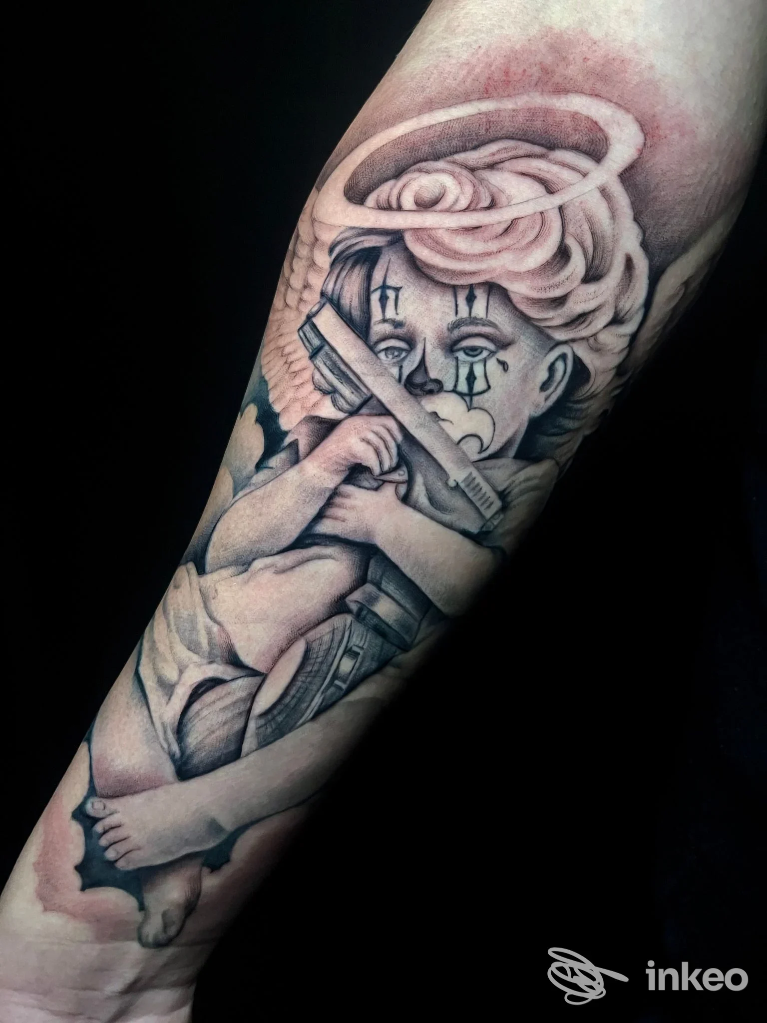 Tatuaggio in bianco e nero su avambraccio presso Prestige Tattoo Studio, Ancona: putto con aureola che tiene due pistole.