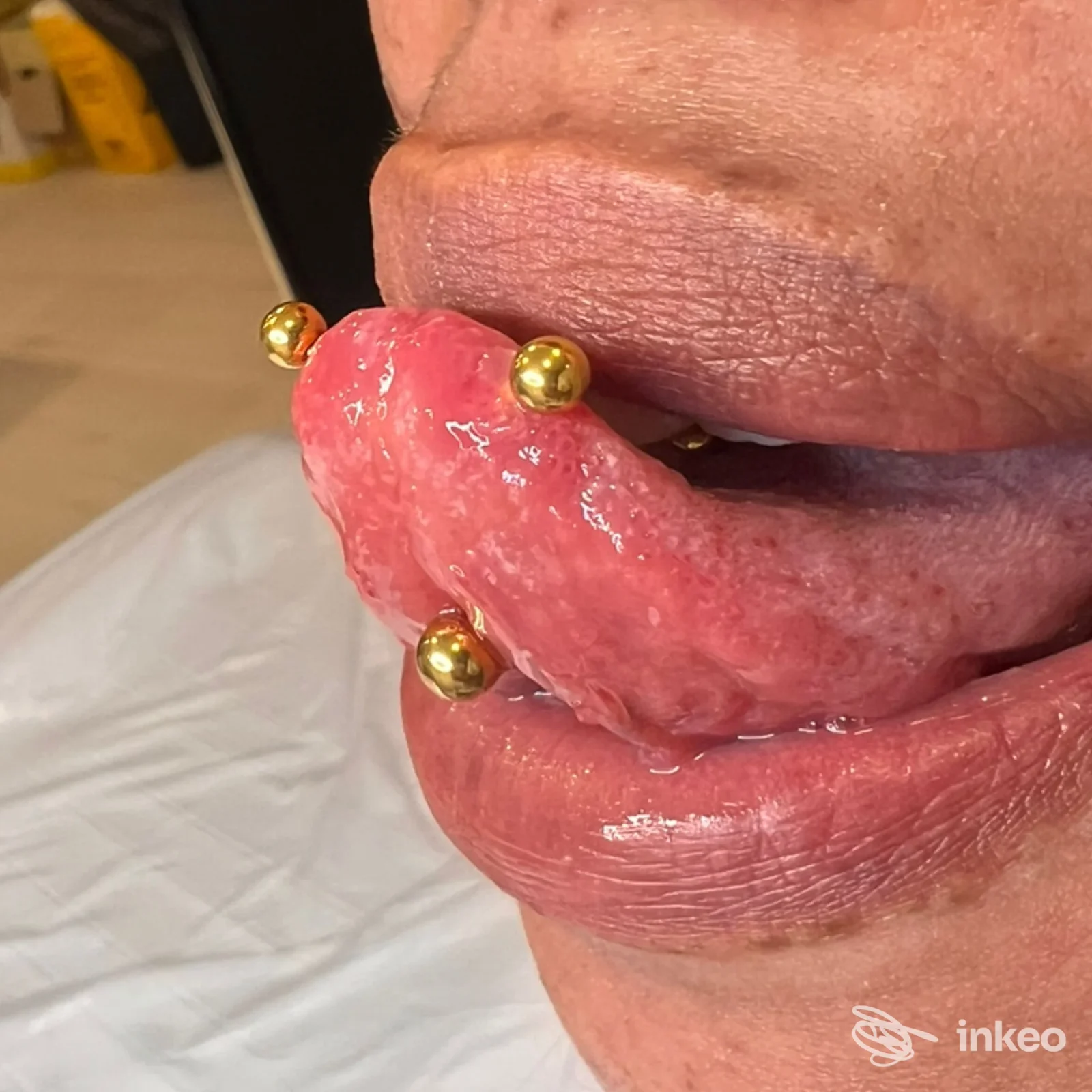 Primo piano di lingua con piercing multipli dorati, scatto realizzato per Yely - Beauty Tattoo & Piercing, Torino.