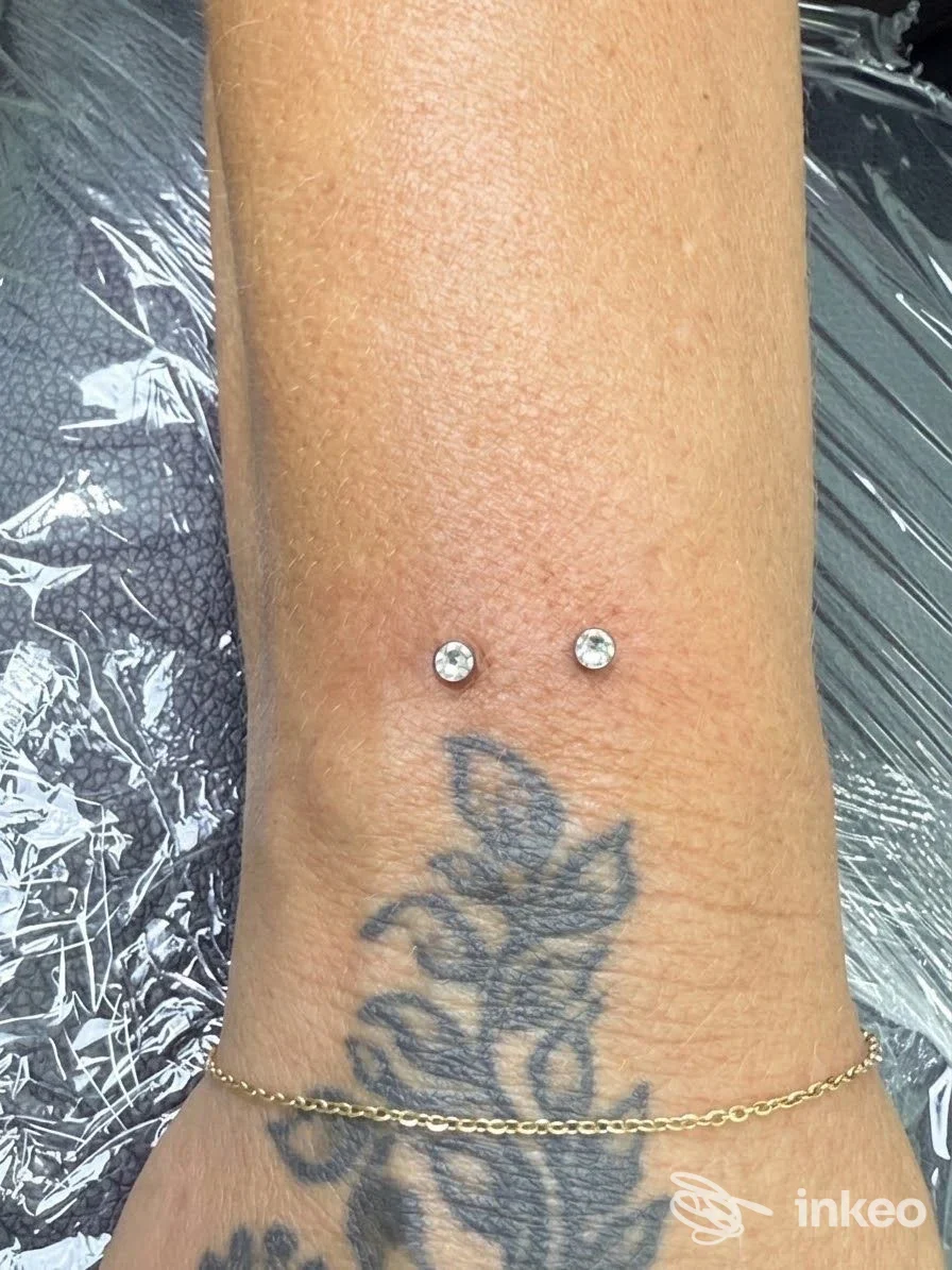 Polso con due micro-dermal piercing sopra un tatuaggio; foto fornita da FOX-INKASTONATO, Senigallia.